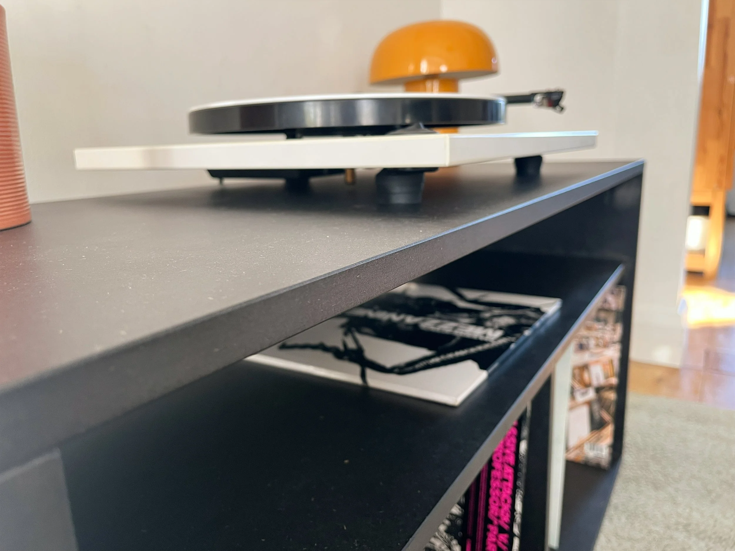 Close-up of a black hifi cabinet with vinyls and record player