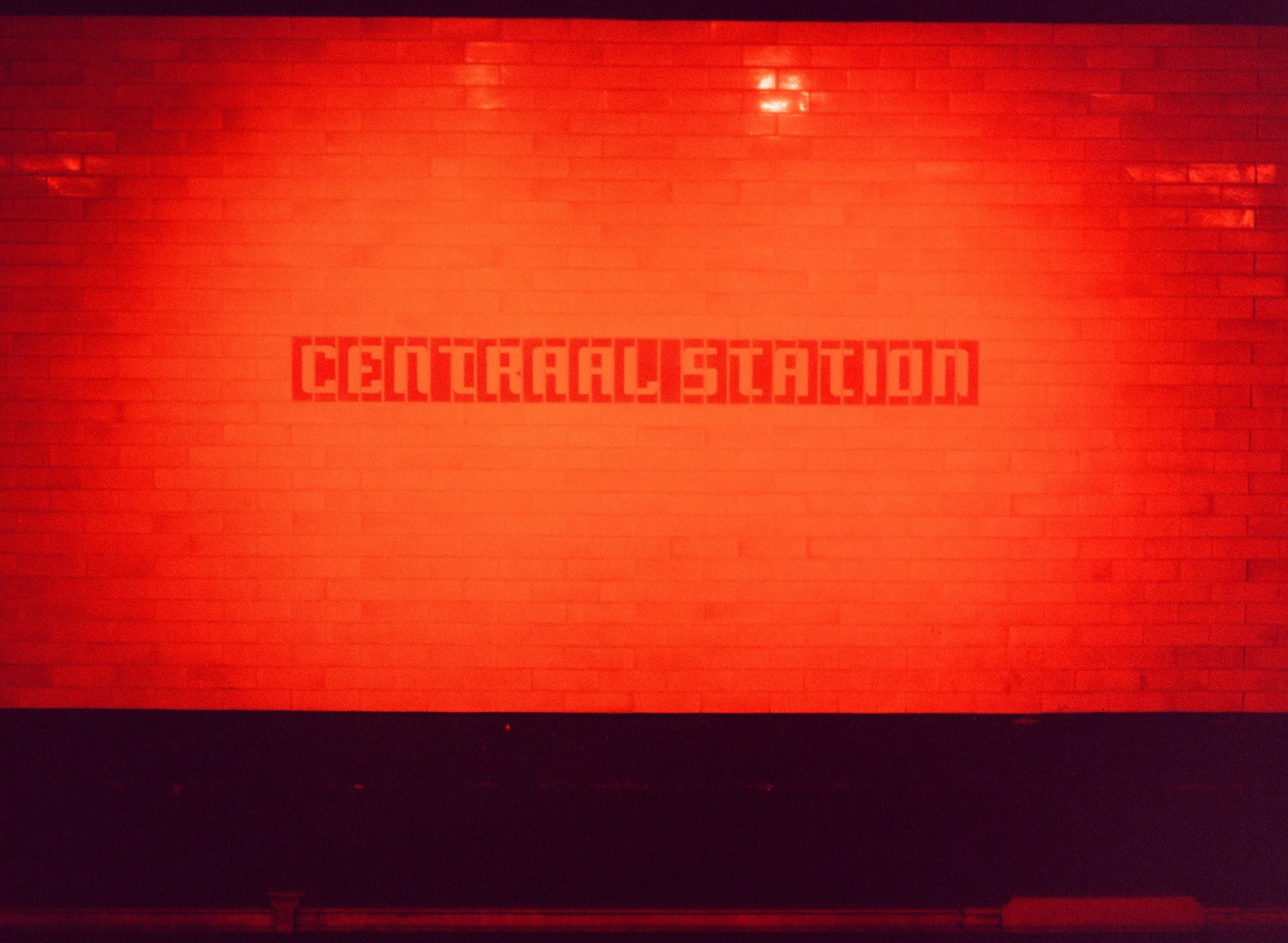 A red brick wall with a sign that reads 'CENTRALE STATION' in pixelated red lettering.