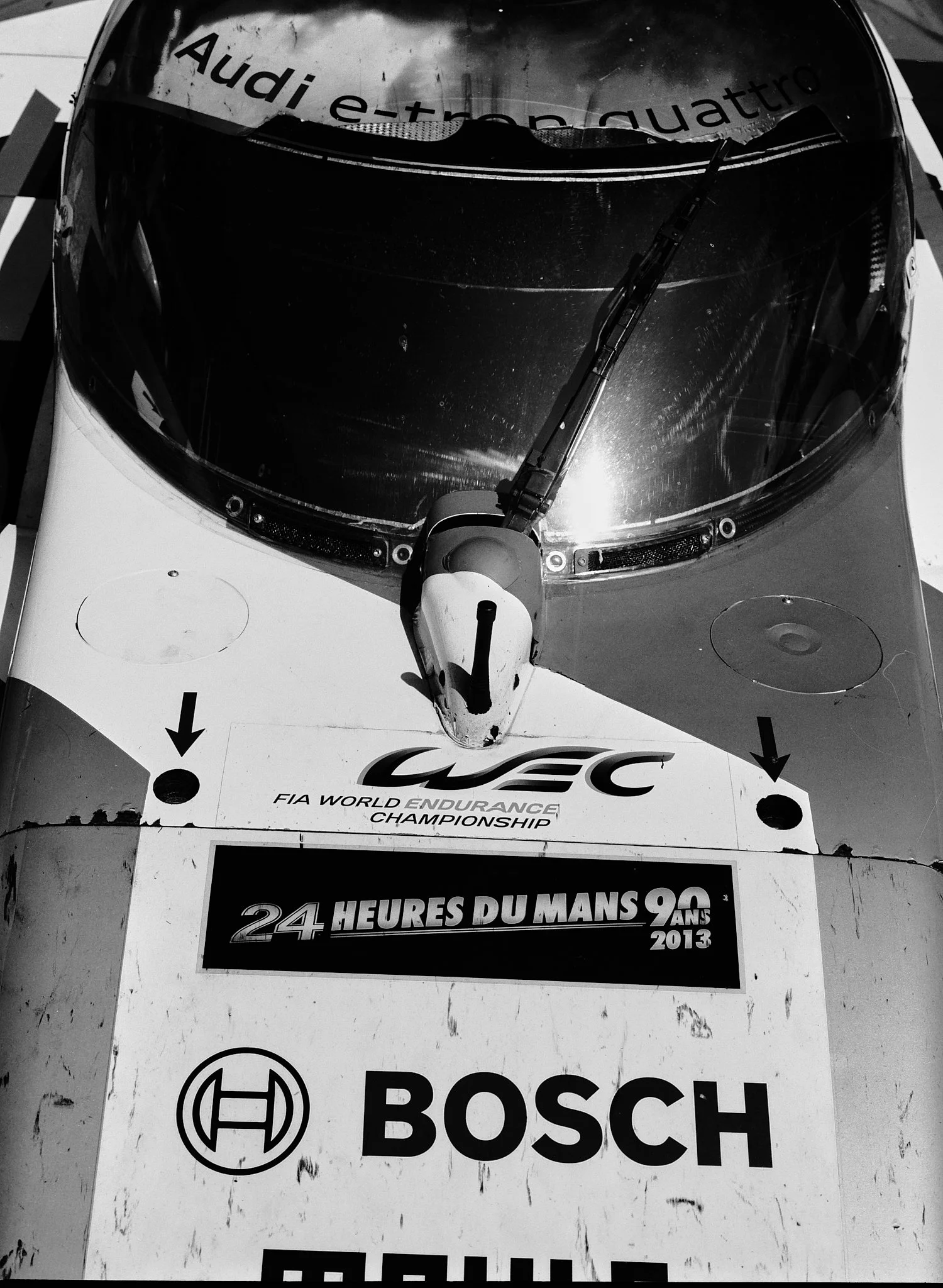 Top view of a race car with a windshield wiper, with logos for Audi, FIA World Endurance Championship, and Bosch. The text indicates a 24-hour race at Le Mans in 2013.