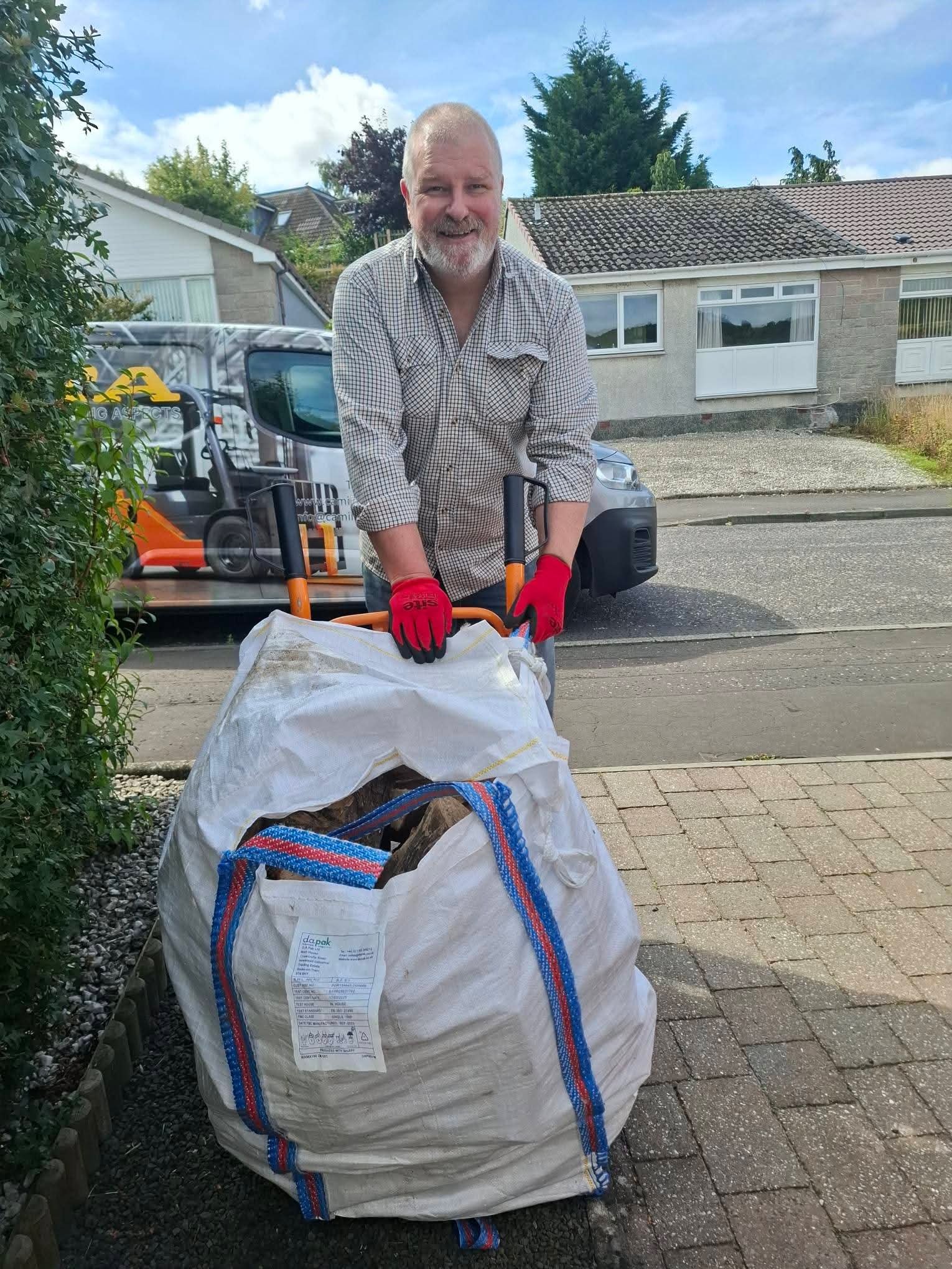 Billy with a barrow bag of firewood on a sack barrow, ready for delivery.