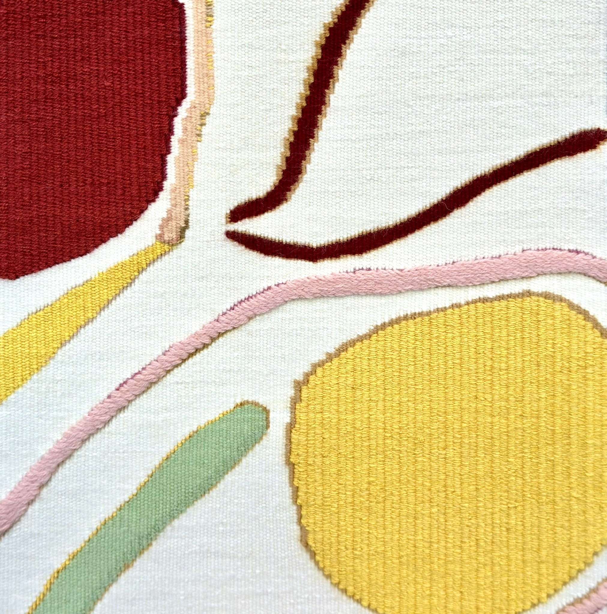 Détail d'un tapis avec des bandes de couleurs pastel comme le rose, le vert, le jaune, le blanc et le rouge, avec des contours dorés.