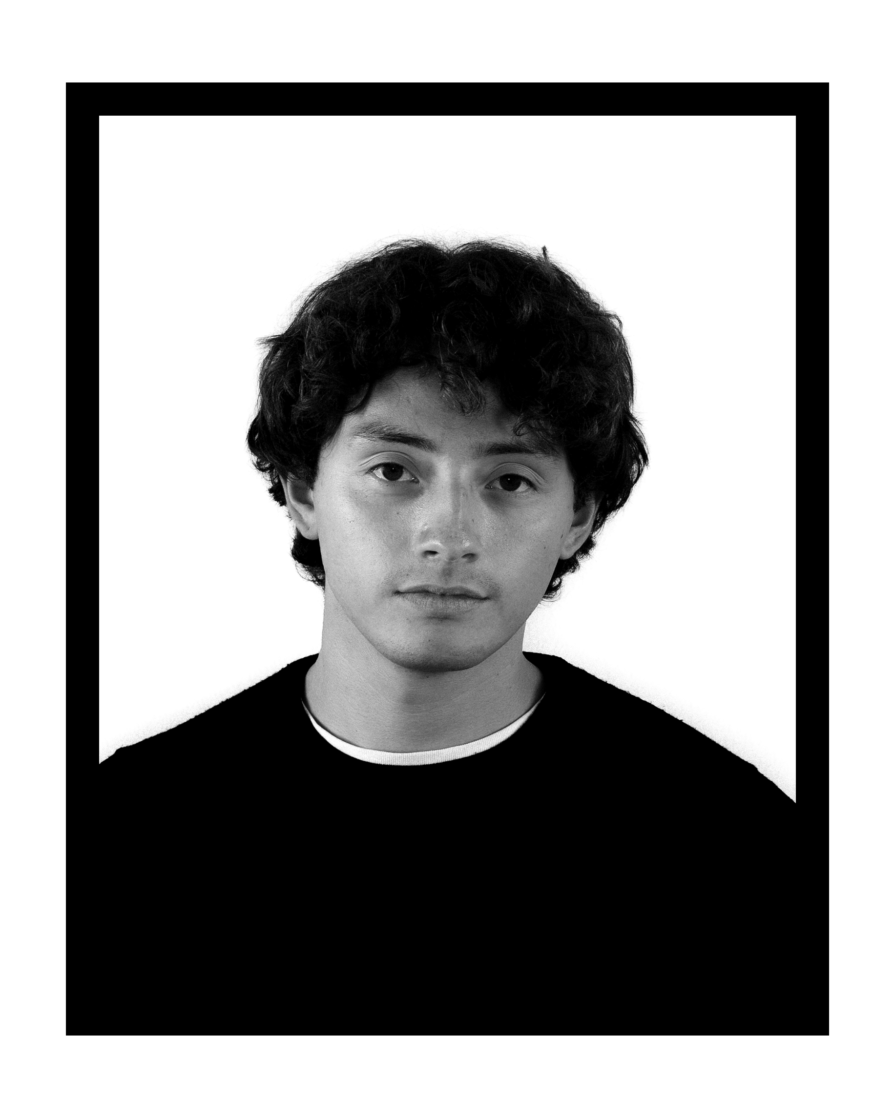 Black-and-white headshot of a young man with curly dark hair wearing a black shirt against a white background