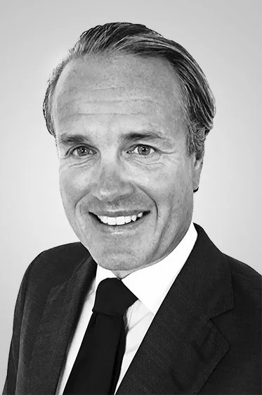 A black-and-white portrait of a smiling man in a suit and tie.