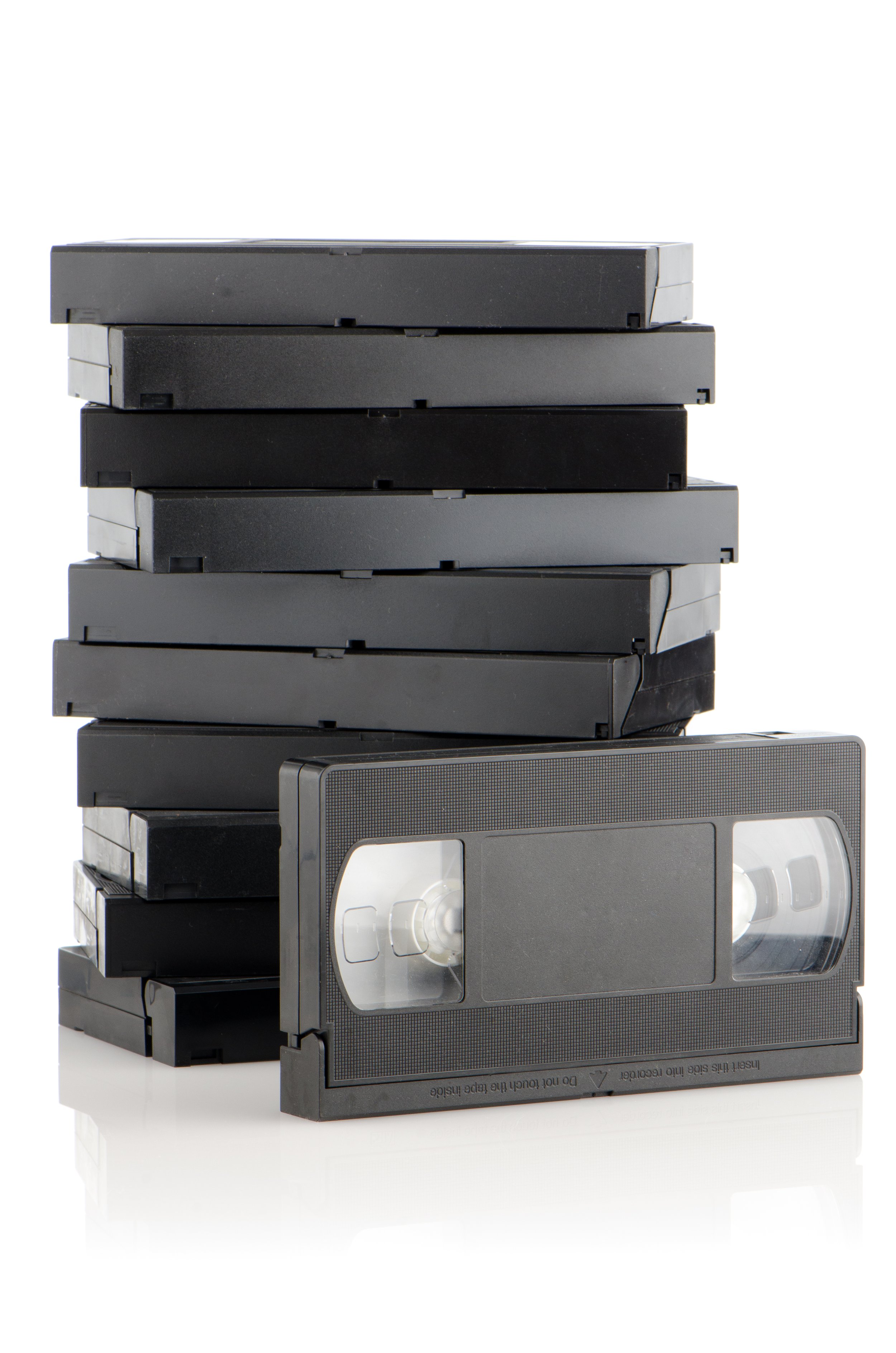 Stack of black and gray VHS tapes, with one tape removed showing the reels inside.