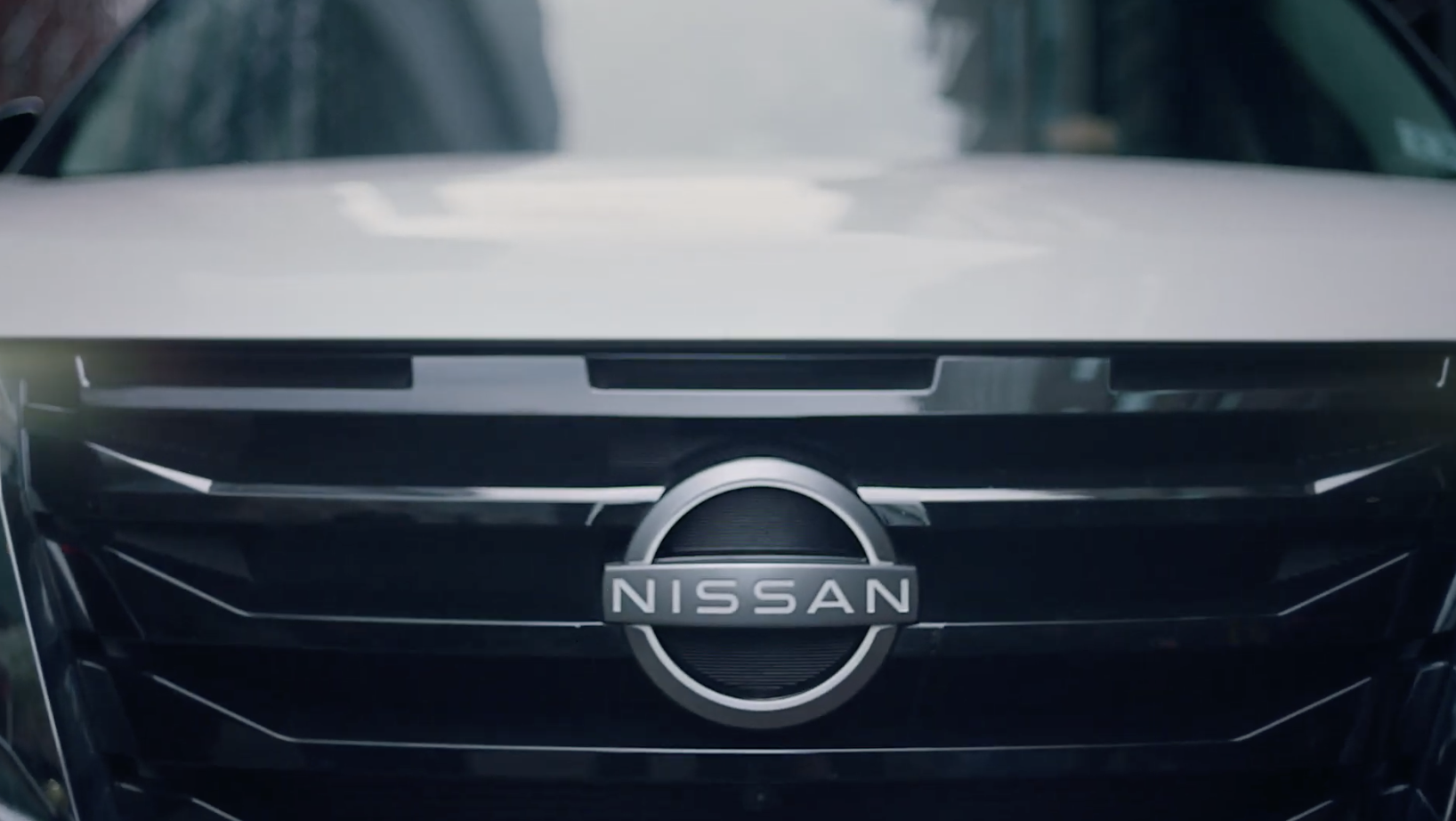 Close-up of the front grille of a black Nissan vehicle with the Nissan logo.