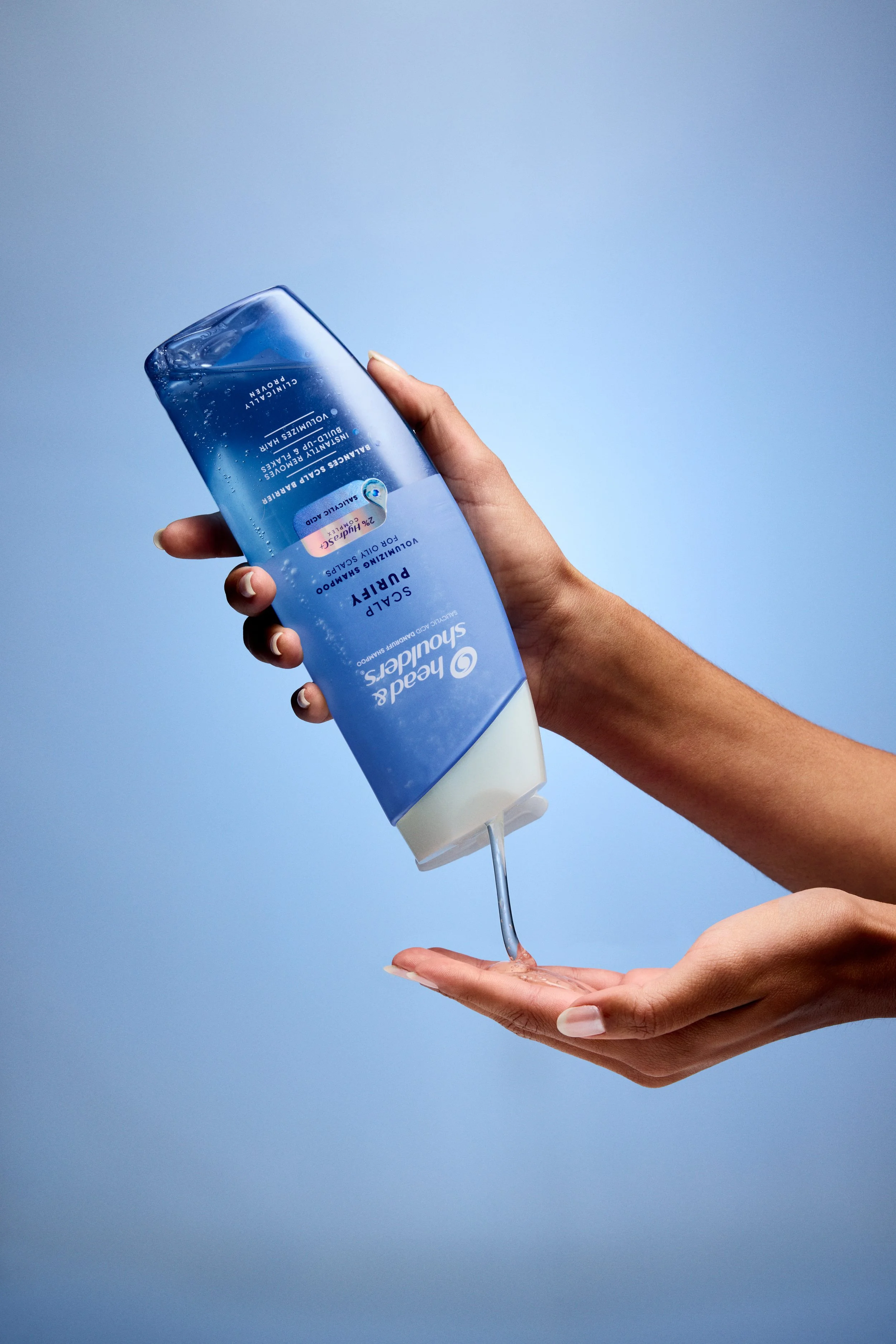 Person dispensing blue facial cleanser from a bottle into their hand