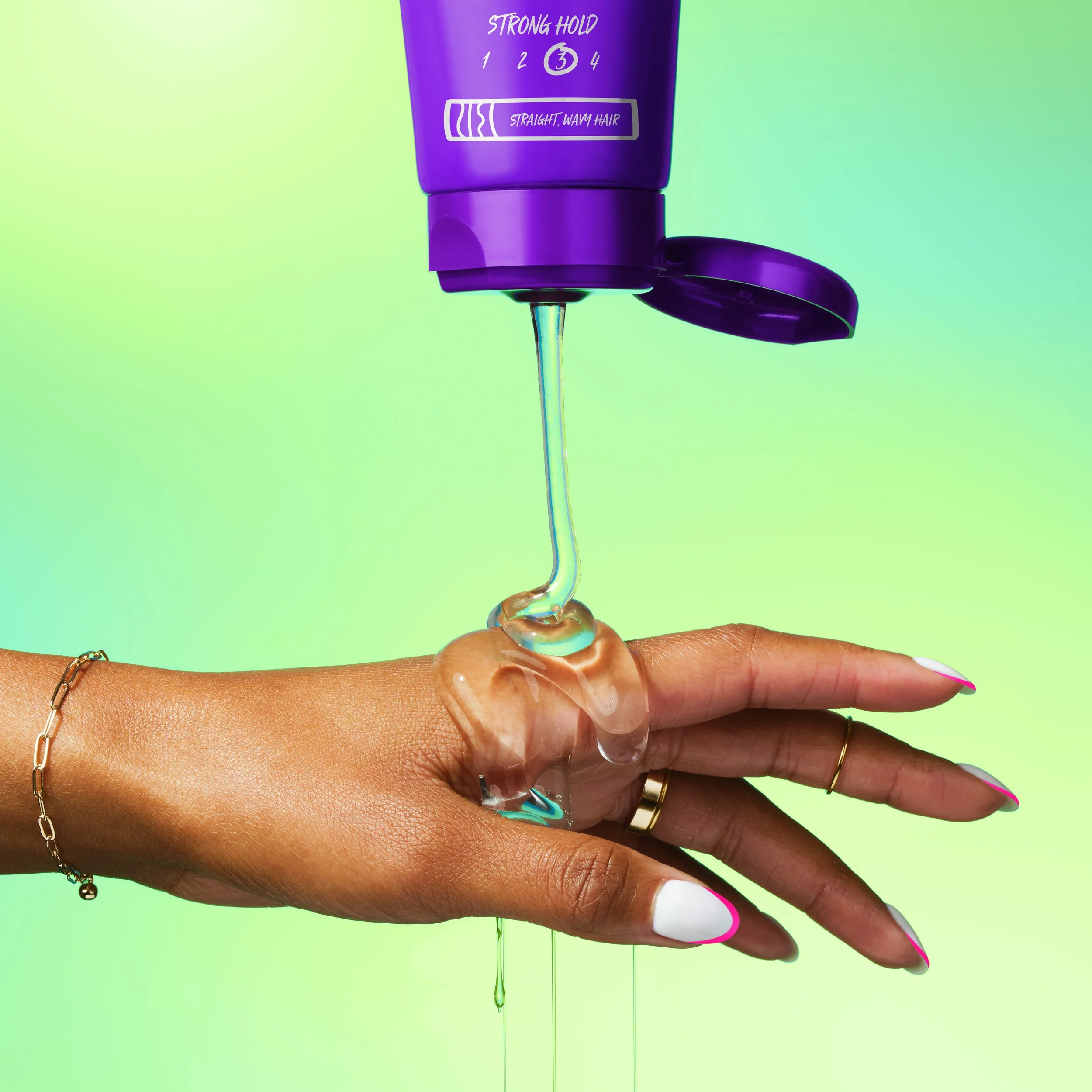 Purple hair gel dispenser labeled strong hold releasing gel onto a manicured hand