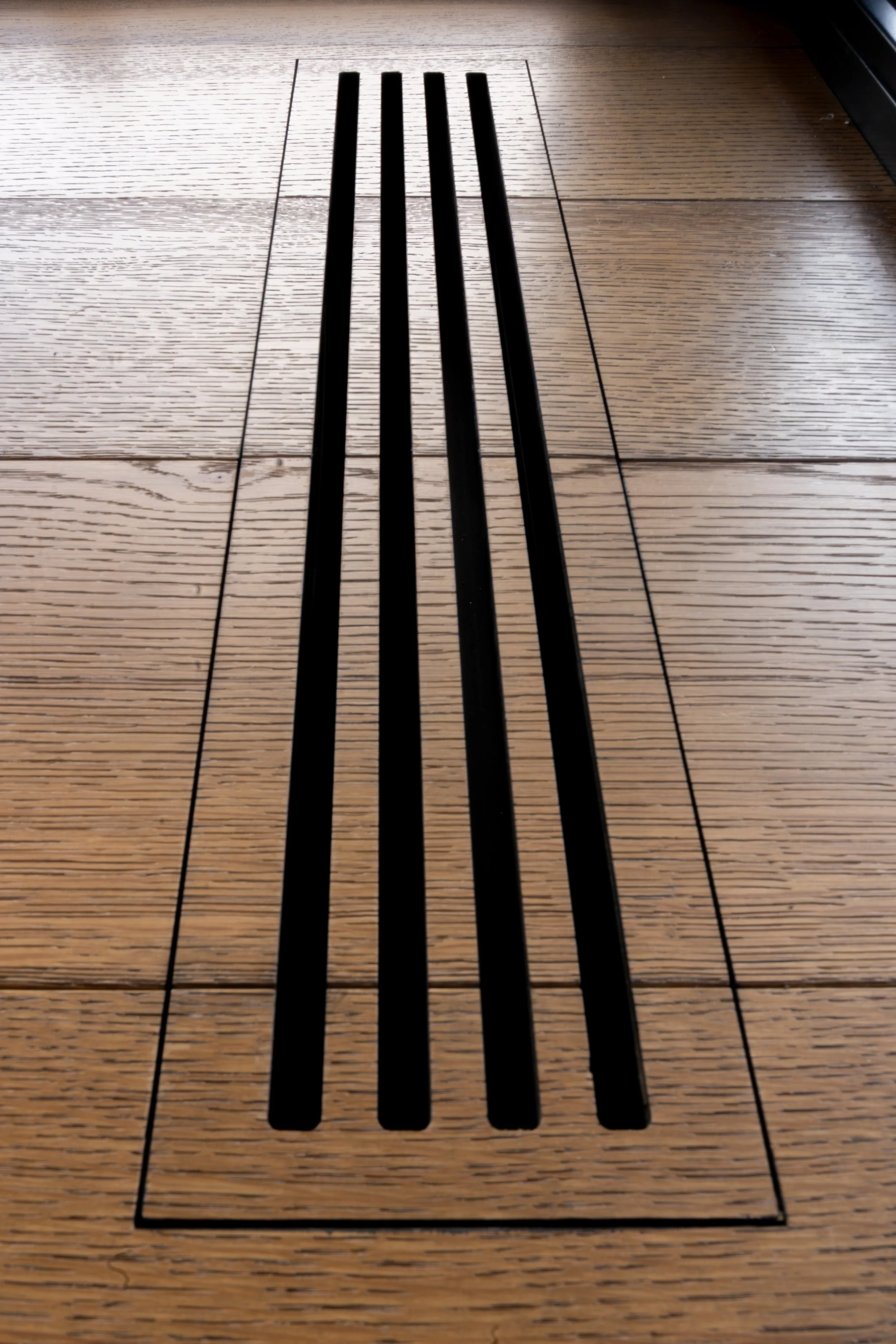 Close-up of a wooden floor with a grain-matched floor vent in the center.