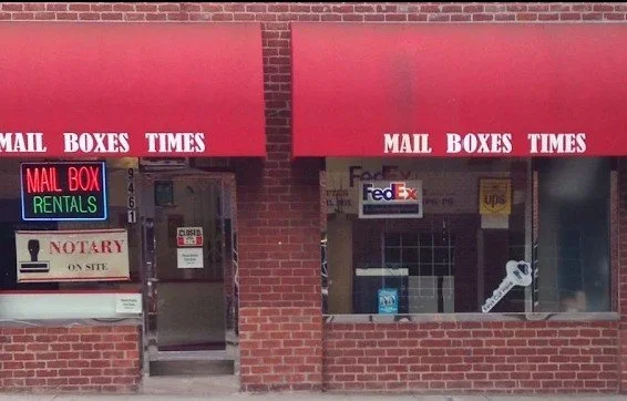 Mail Boxes Times storefront with red awnings and Mail Box Rentals neon sign