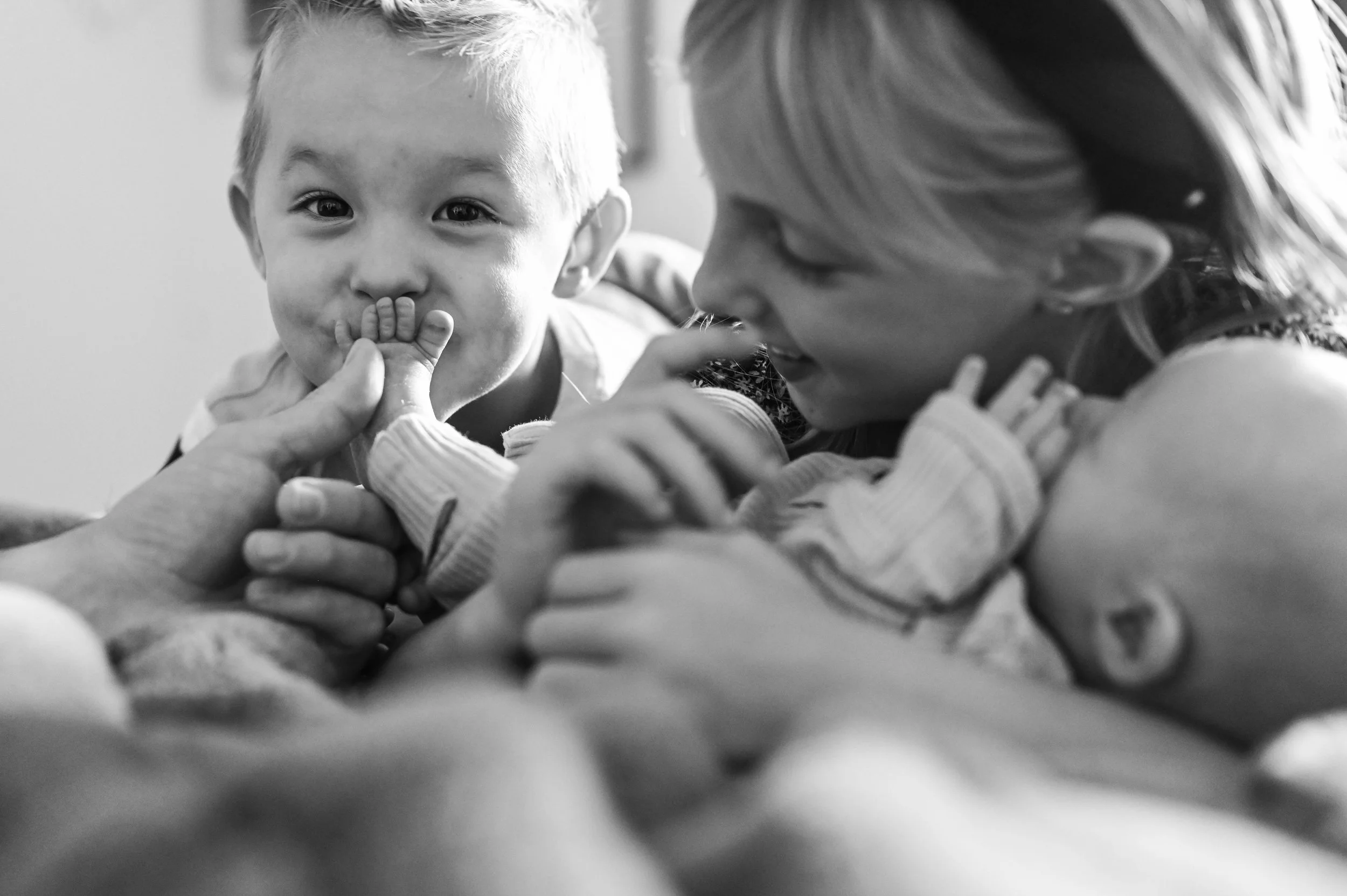 Close-up black and white photo of a woman and a boy engaging in a playful thumb wrestling match, smiling and enjoying the moment.