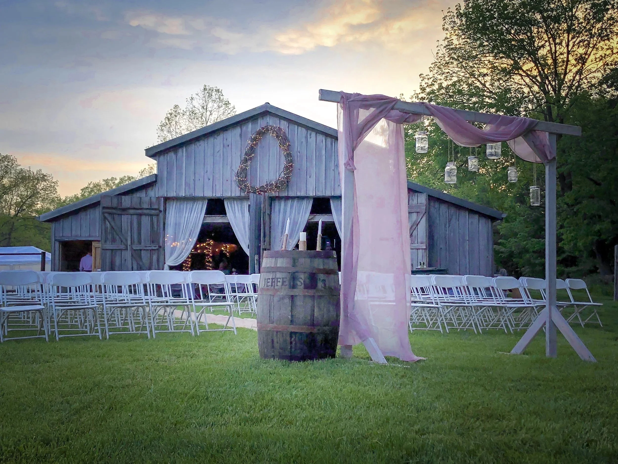 Ceremony arch with purple drapes in front of the barn