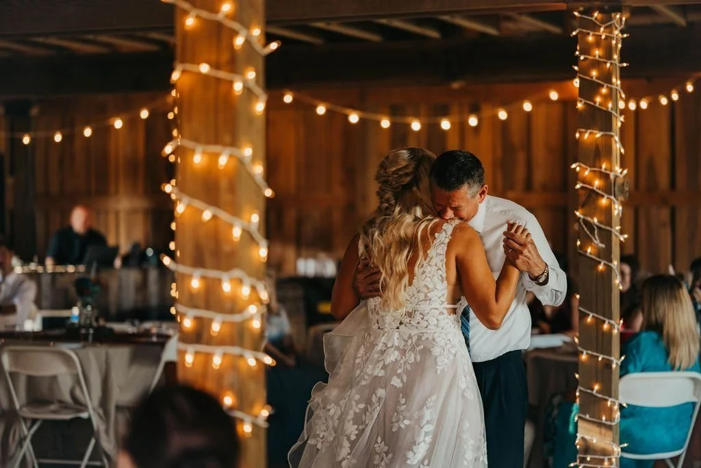 Couple's first dance under string lights inside the barn