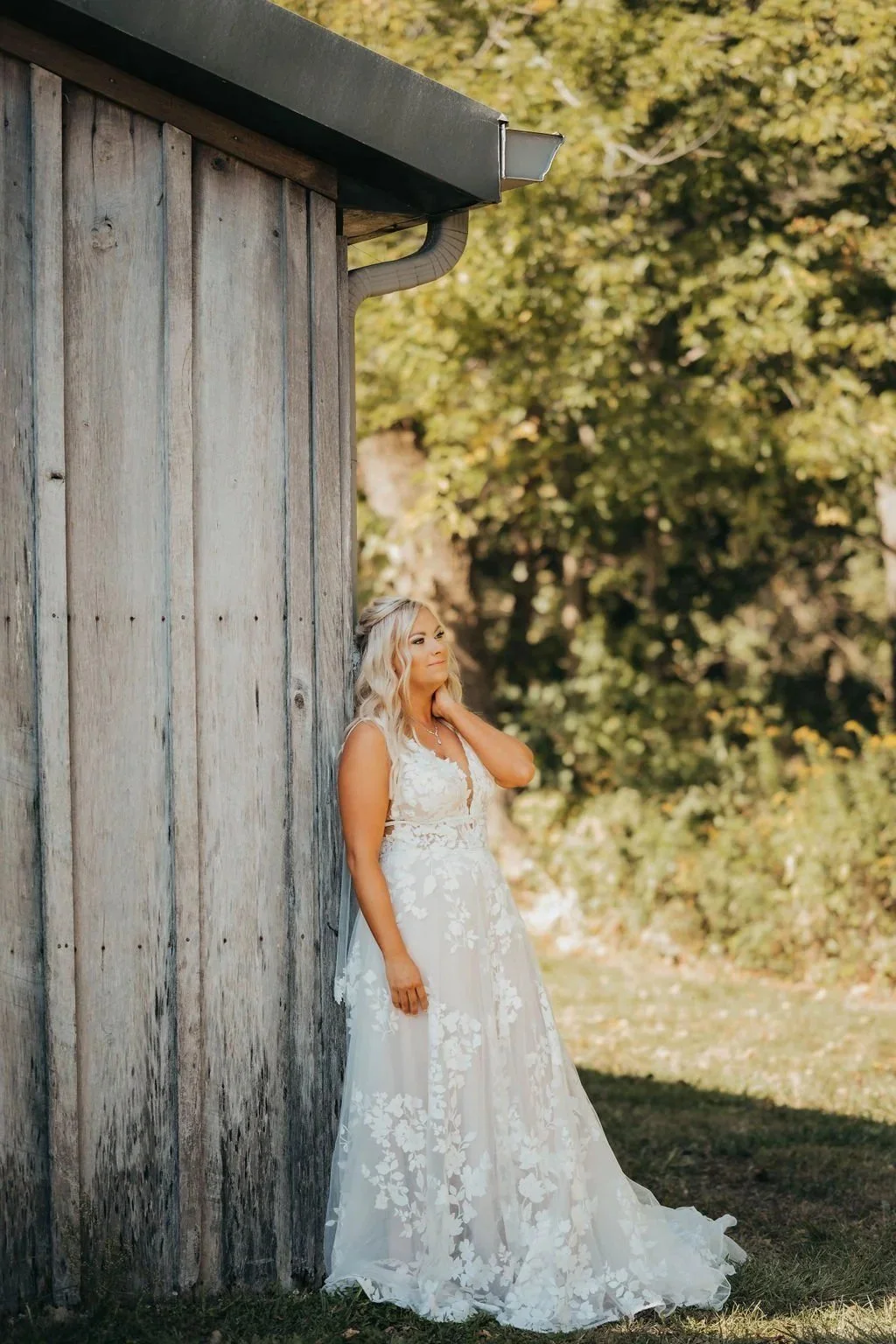 Bride leaning against the weathered barn siding
