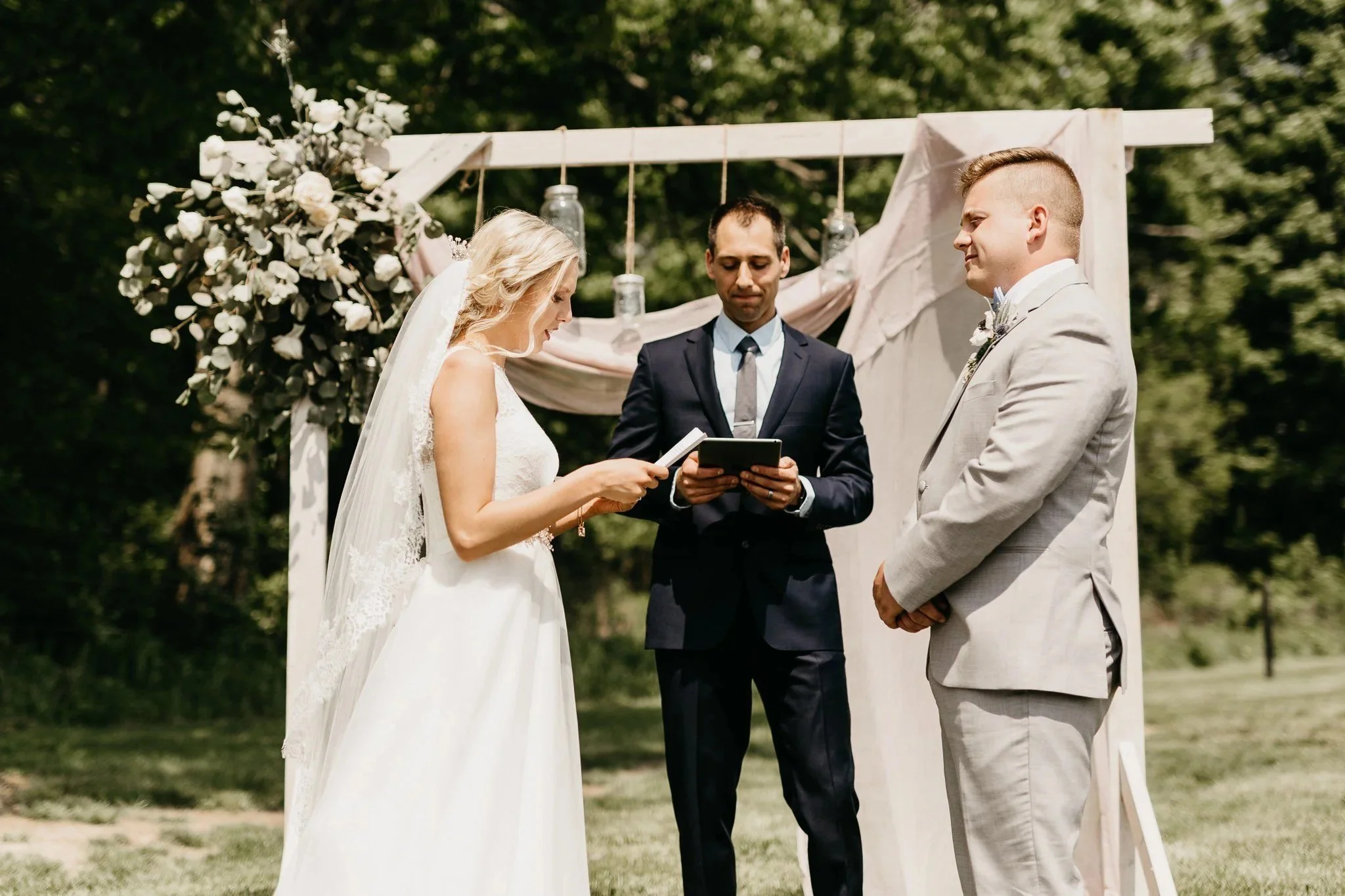 Couple reading vows under the wooden ceremony arch