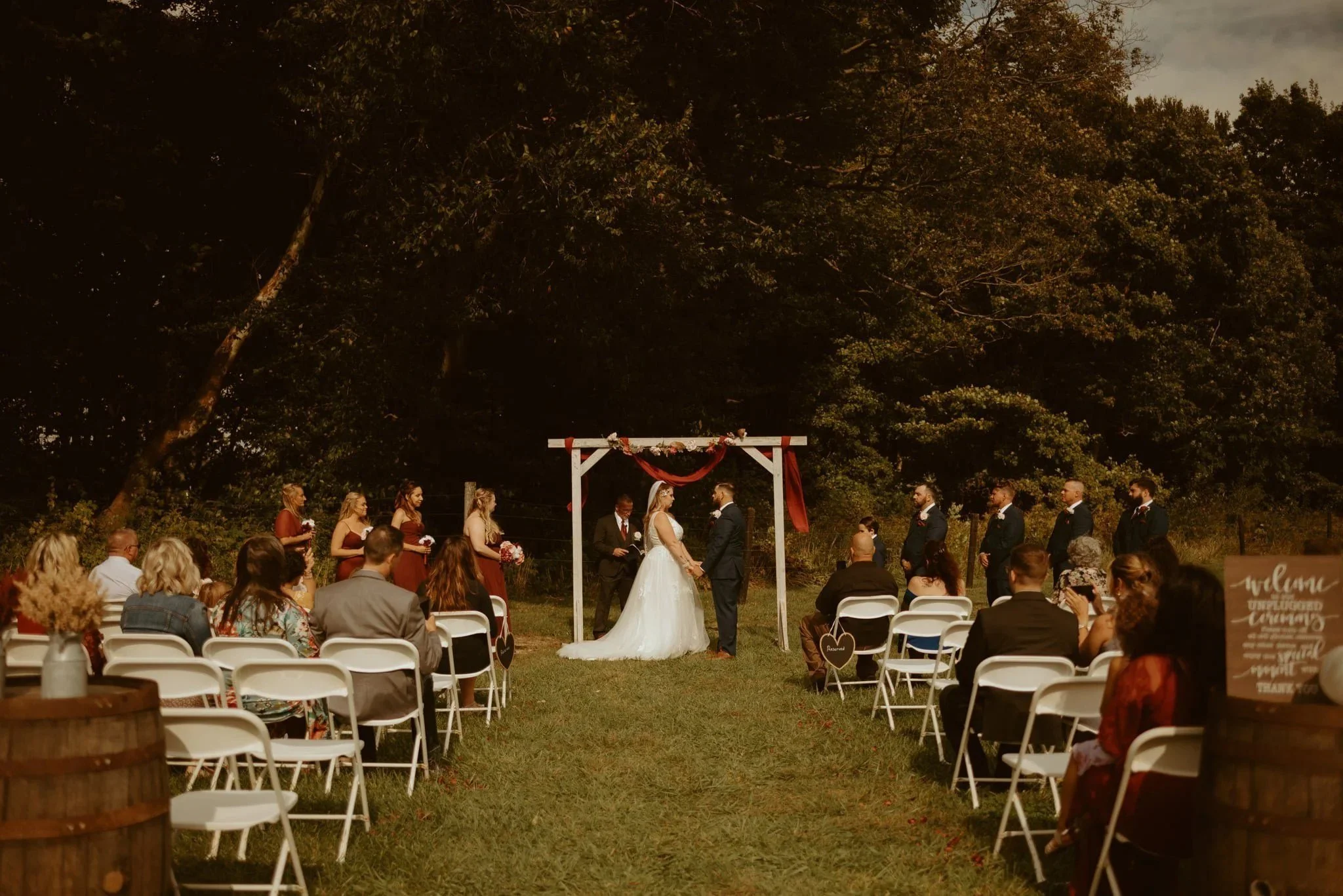 Evening wedding ceremony under the wooden arch at Hidden Brook Acres