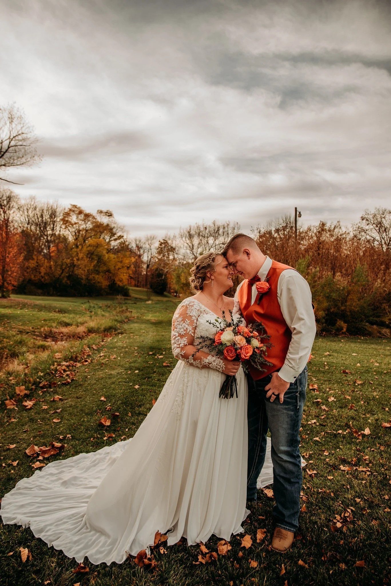 Bride and groom touching foreheads in the fall countryside