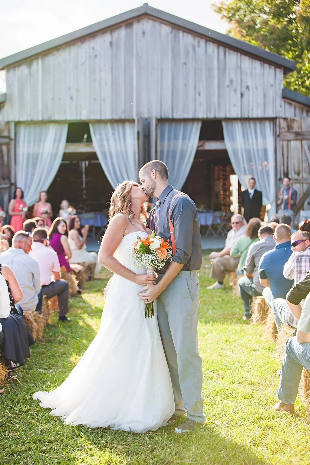 Couple kissing at the end of the aisle during an outdoor barn ceremony