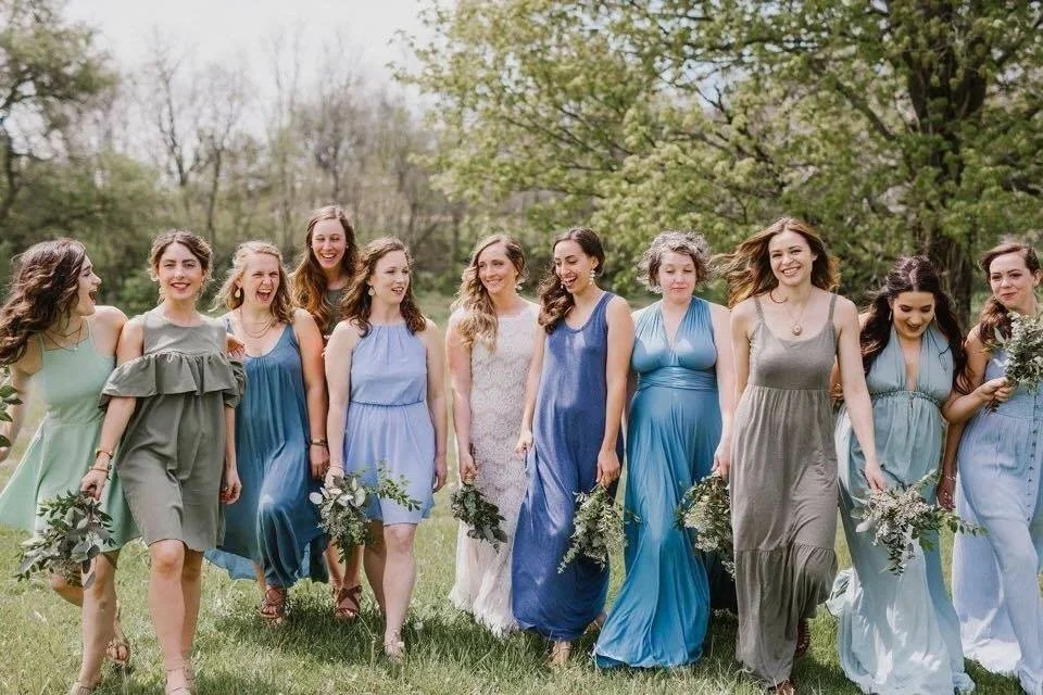 Bridesmaids in mismatched blue and gray dresses holding bouquets