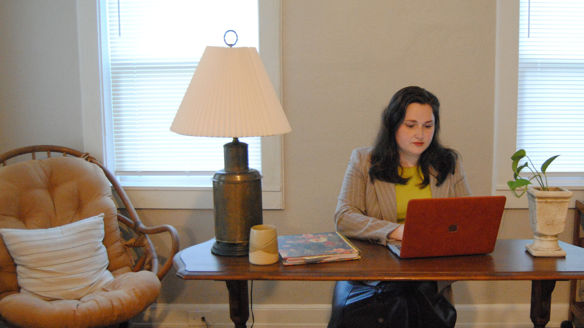 Woman working on a red laptop at a wooden table in a living room
