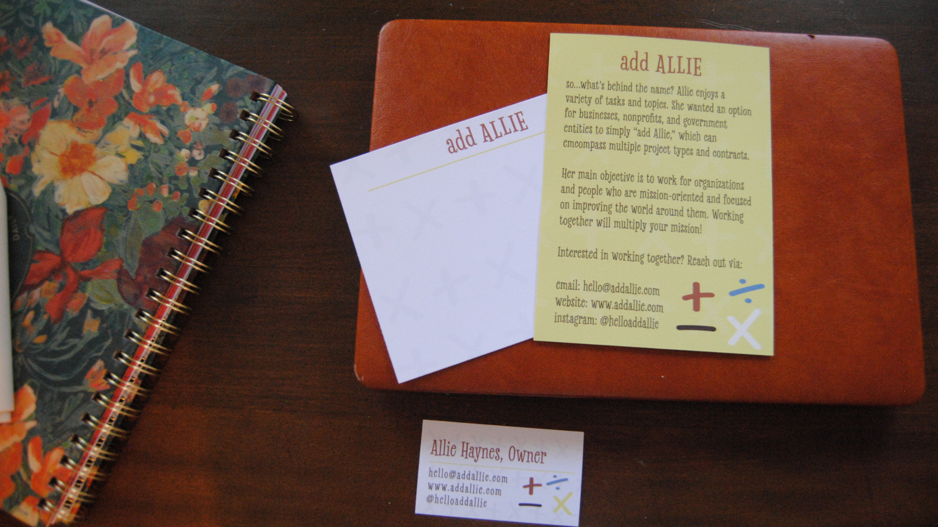 Add Allie business cards and informational flyer on a red folder beside a floral spiral notebook