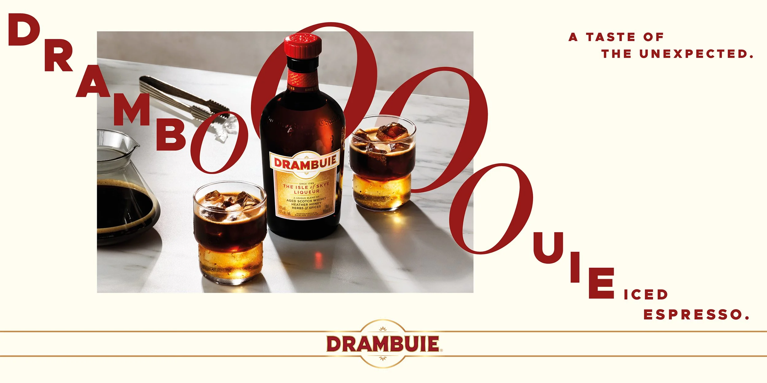 Drambuie bottle beside two iced espresso cocktails on a marble table, with the slogan “A taste of the unexpected”