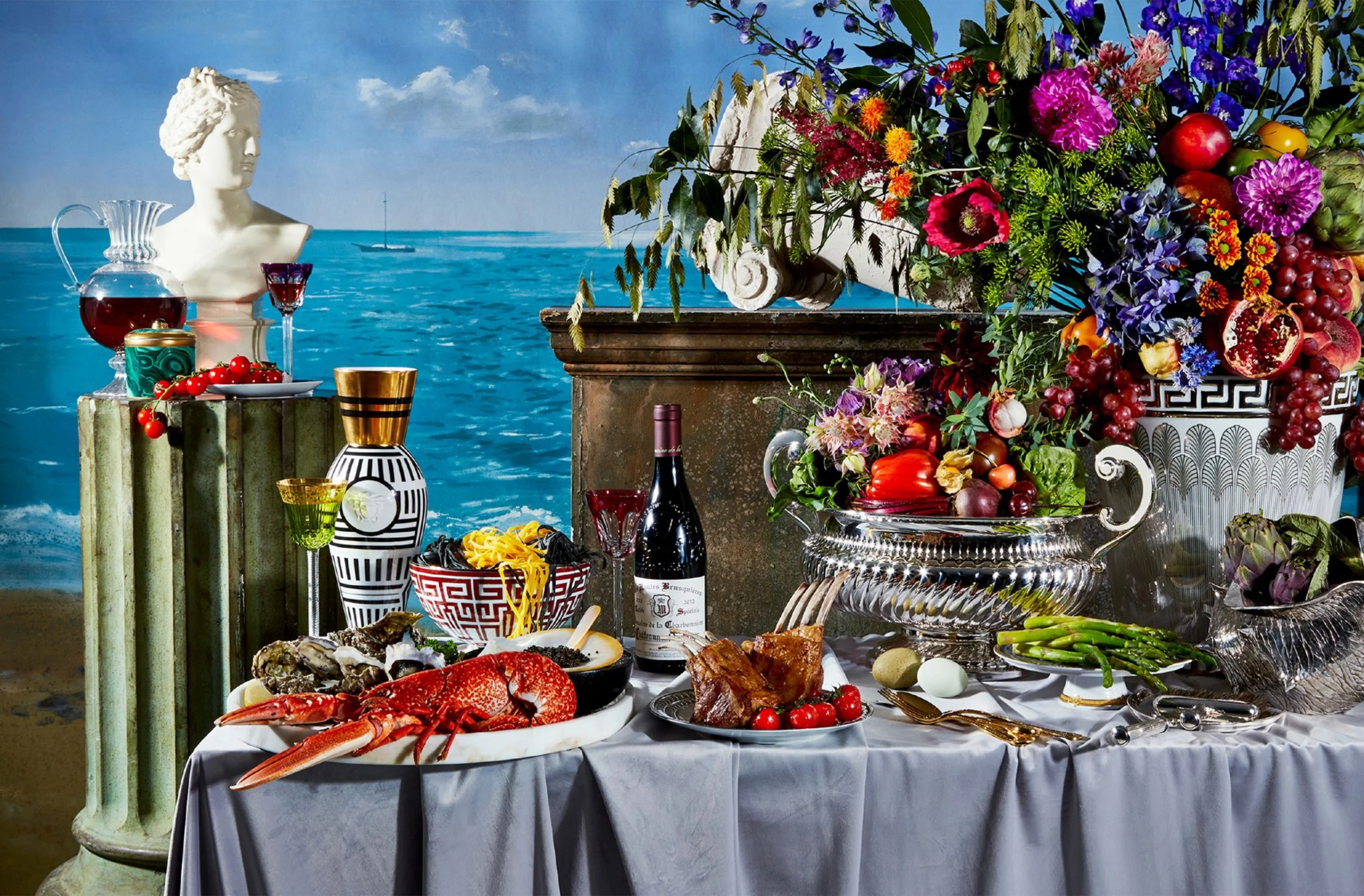 Luxurious seaside banquet table with lobster, oysters, roast duck, vegetables, fruit, wine, colorful flowers, and a classical statue