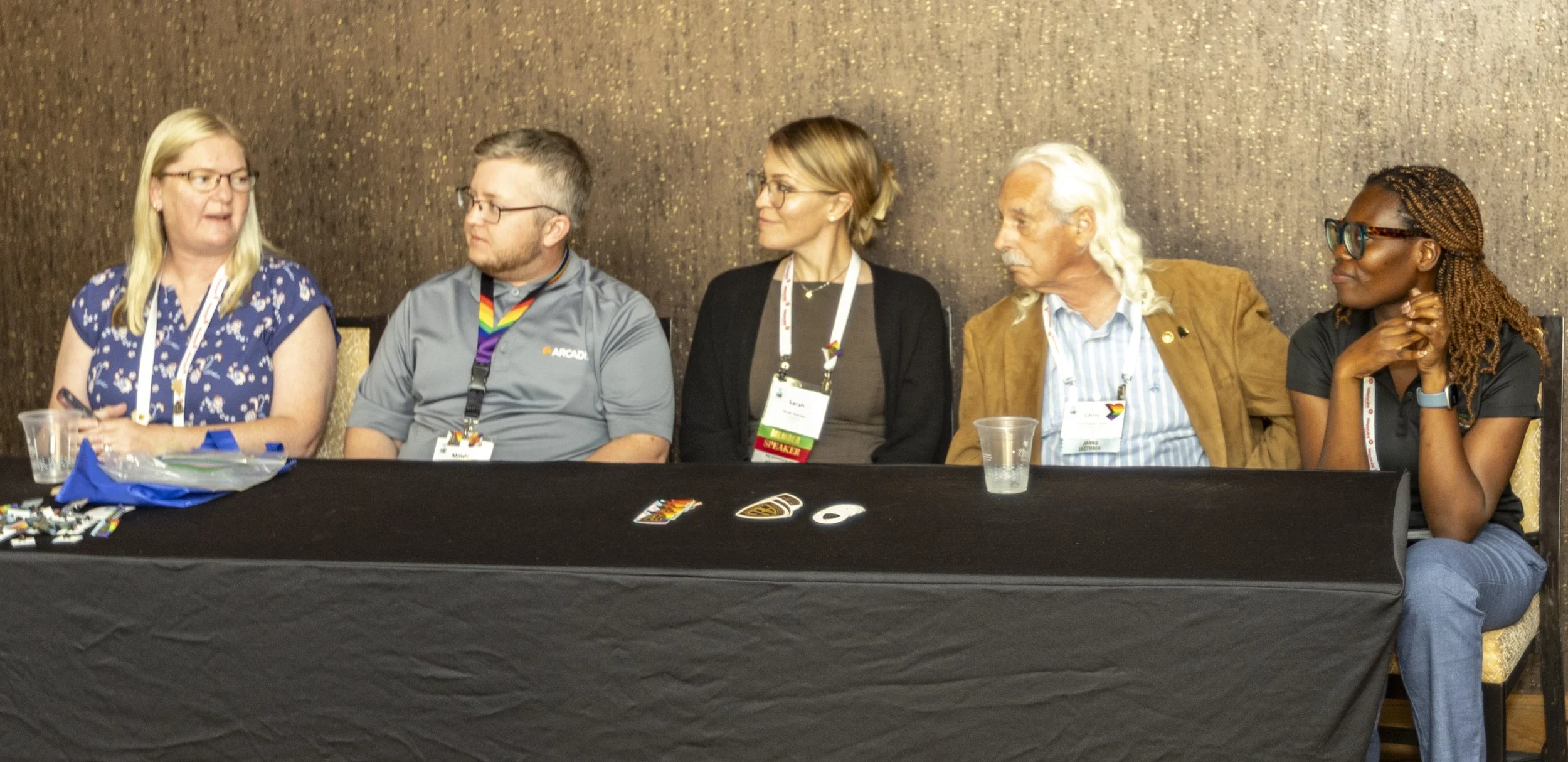 Five panelists seated behind a table at a conference discussion
