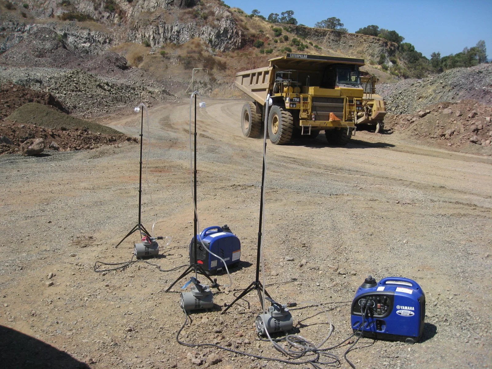 Caterpillar haul truck at a rocky quarry with portable generators and equipment in the foreground