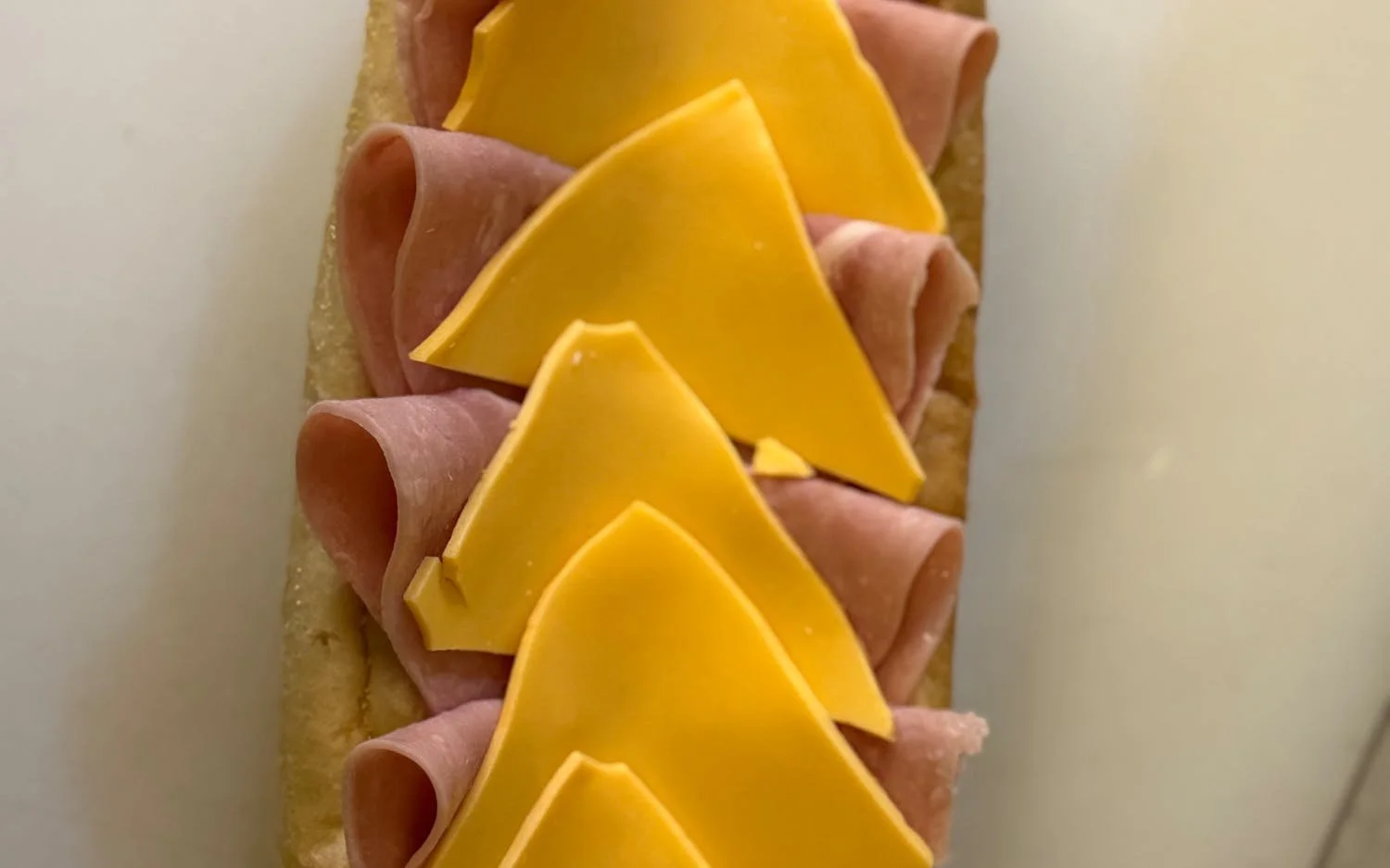 A sandwich with slices of cheese and ham on a bread roll.