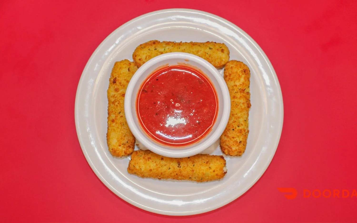 Fried mozzarella sticks with marinara sauce in a small bowl on a white plate