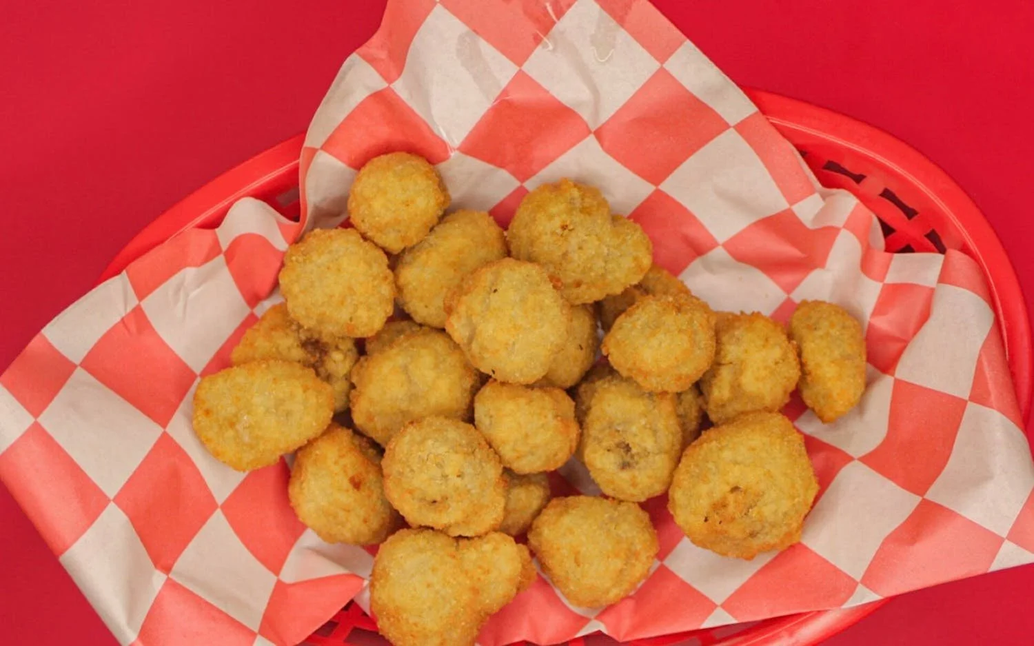 A basket of fried chicken nuggets on red and white checkered paper.