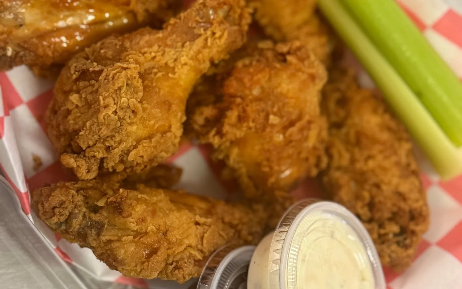 Fried chicken drumsticks with a side of celery sticks and dipping sauce.