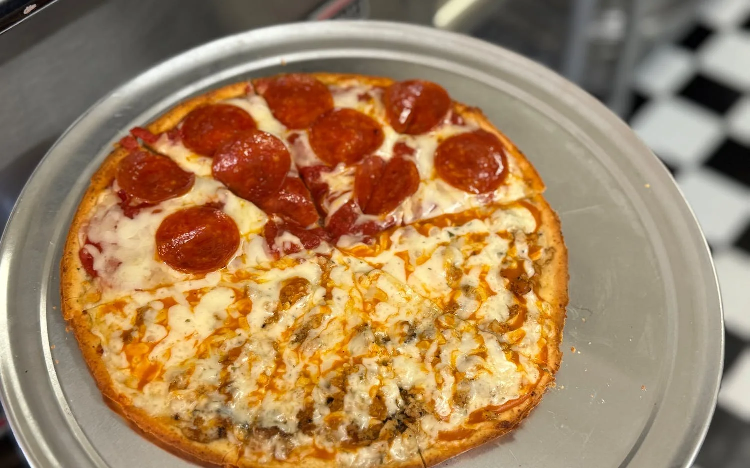 Pepperoni pizza with cheese on a metal tray.