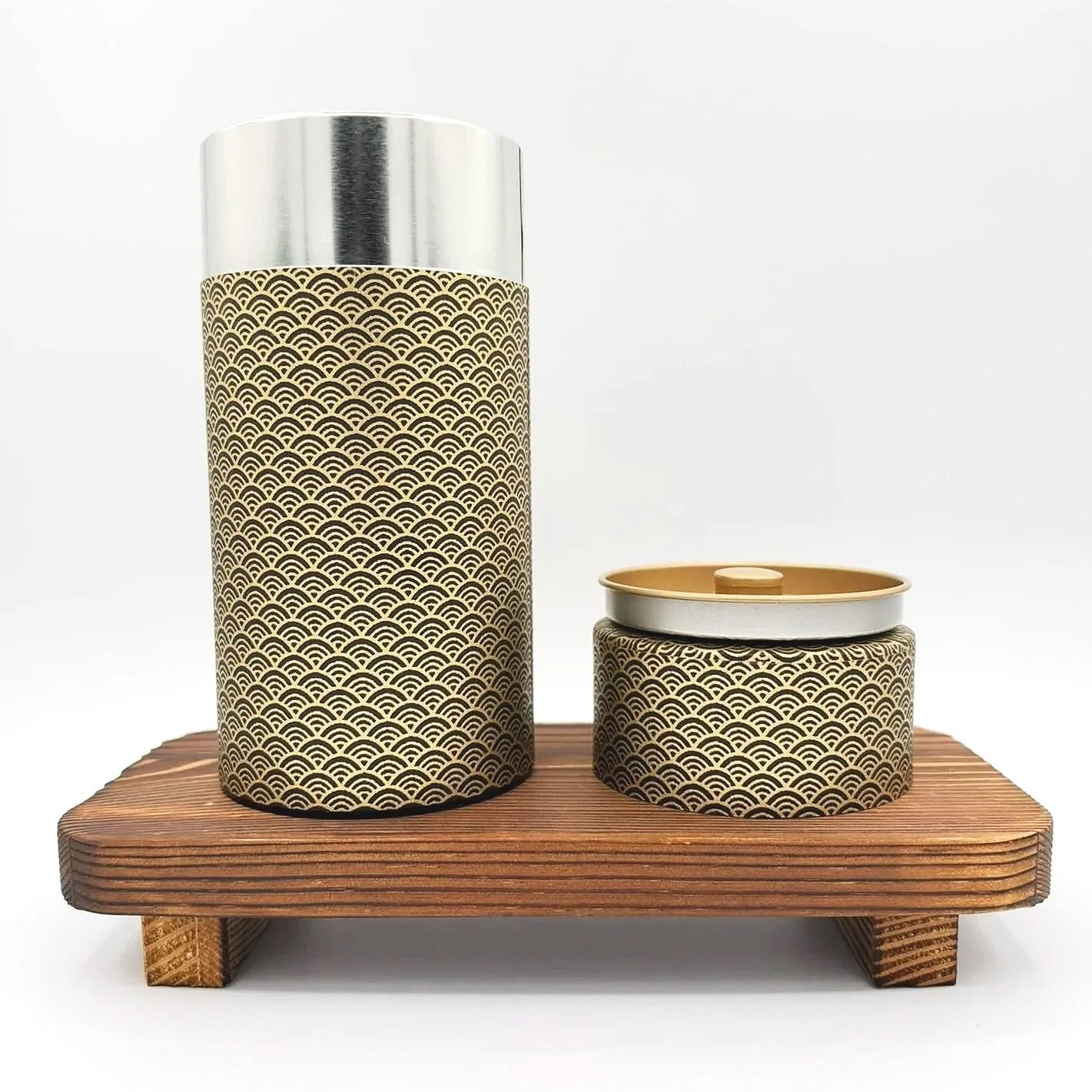 Two decorative cans with Japanese wave pattern, one tall and one short, placed on a wooden stand against a white background.