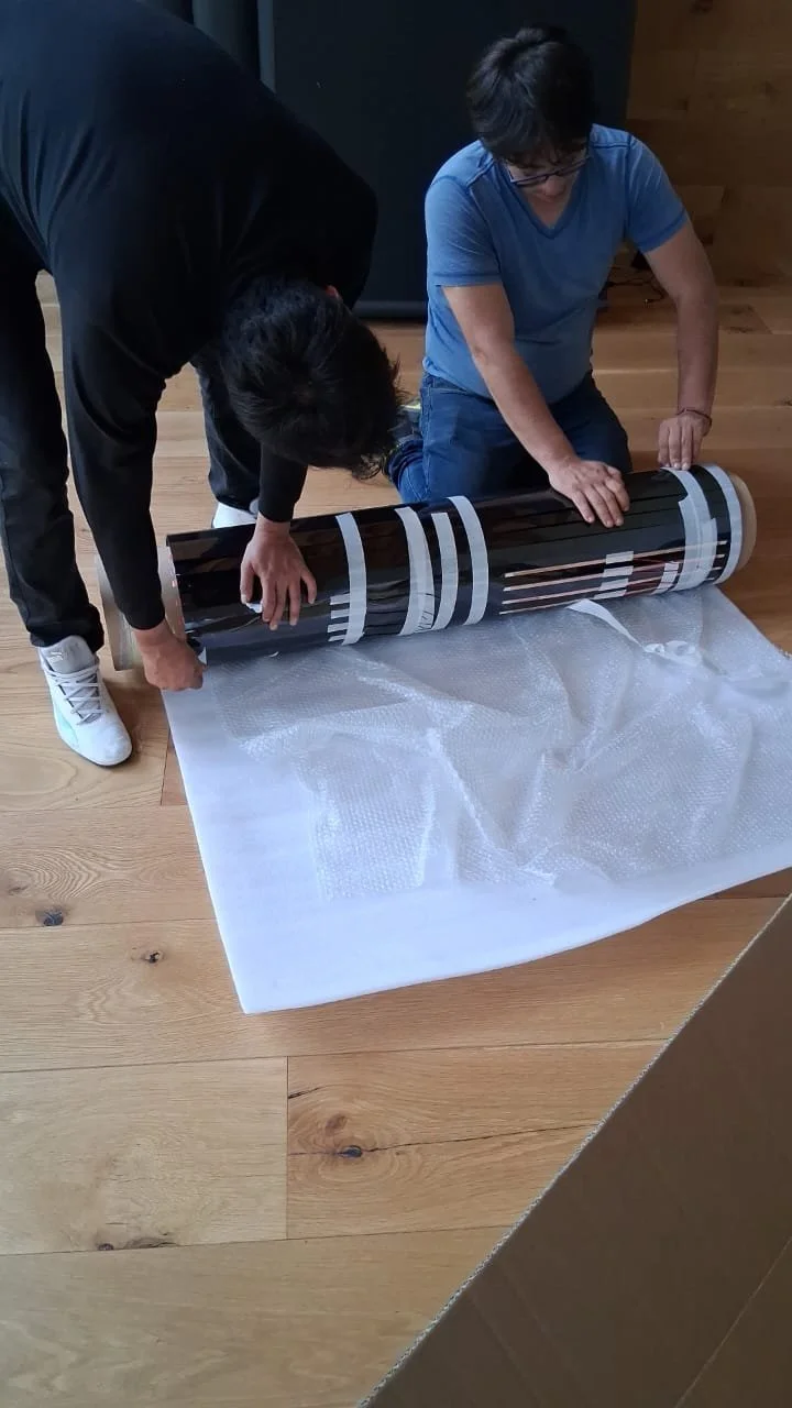 Dos personas preparando el smart film negro para su instalacion, con protección de burbujas de aire debajo.