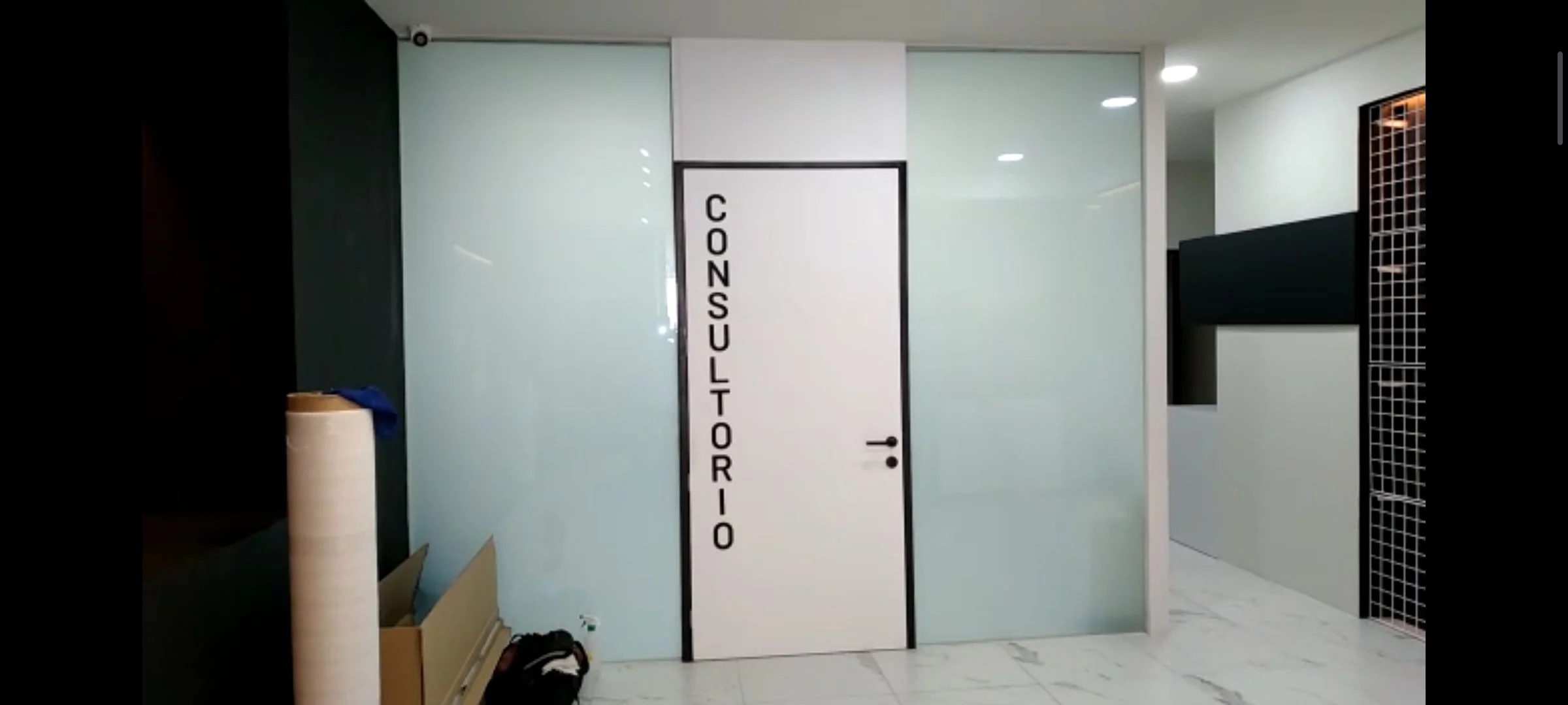 Smart Film opaco instaldo en Puerta con la palabra 'CONSULTORIO' escrita verticalmente en negro en un espacio interior moderno.