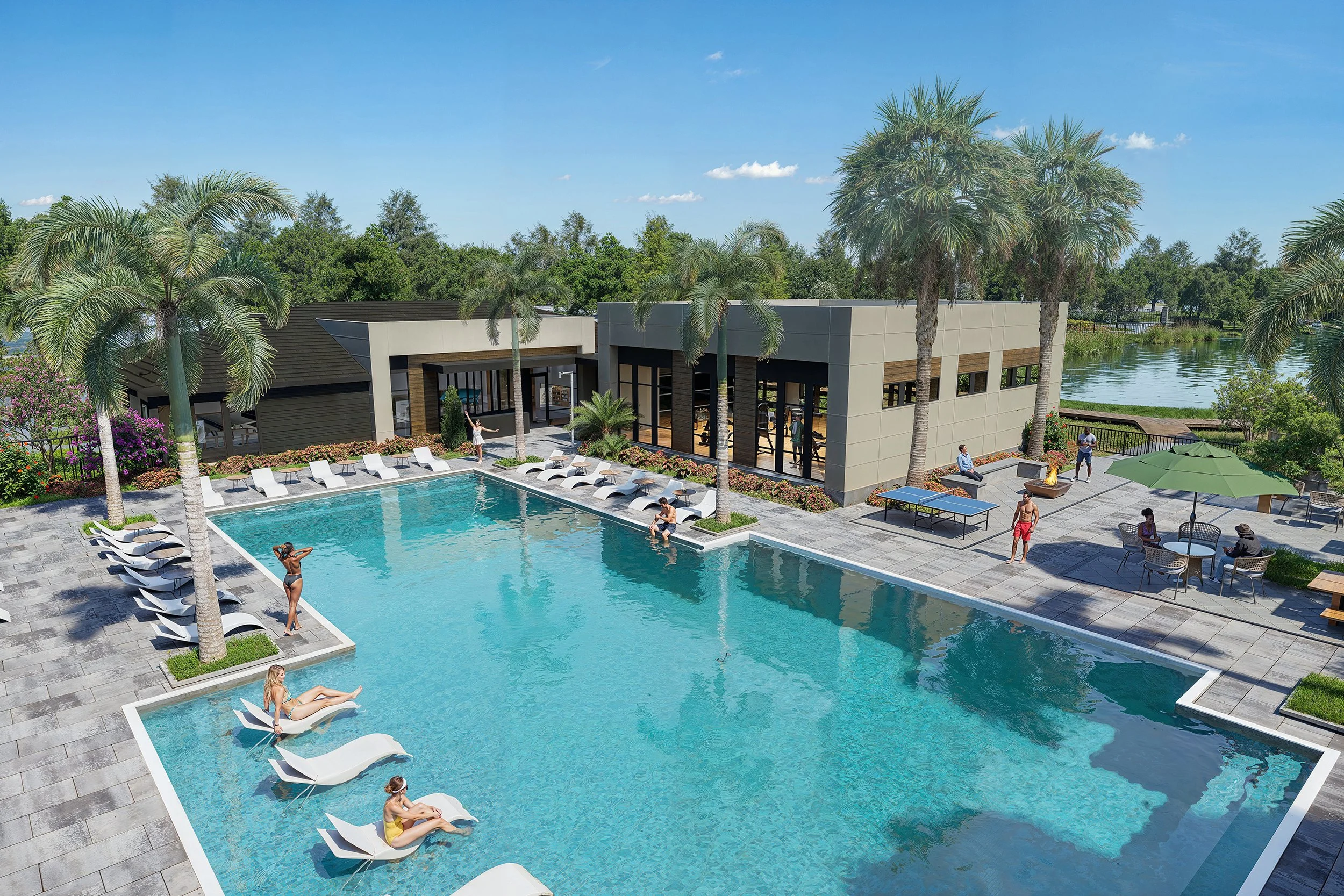 A swimming pool area with lounge chairs and palm trees, overlooking a building and a lake under a clear blue sky.