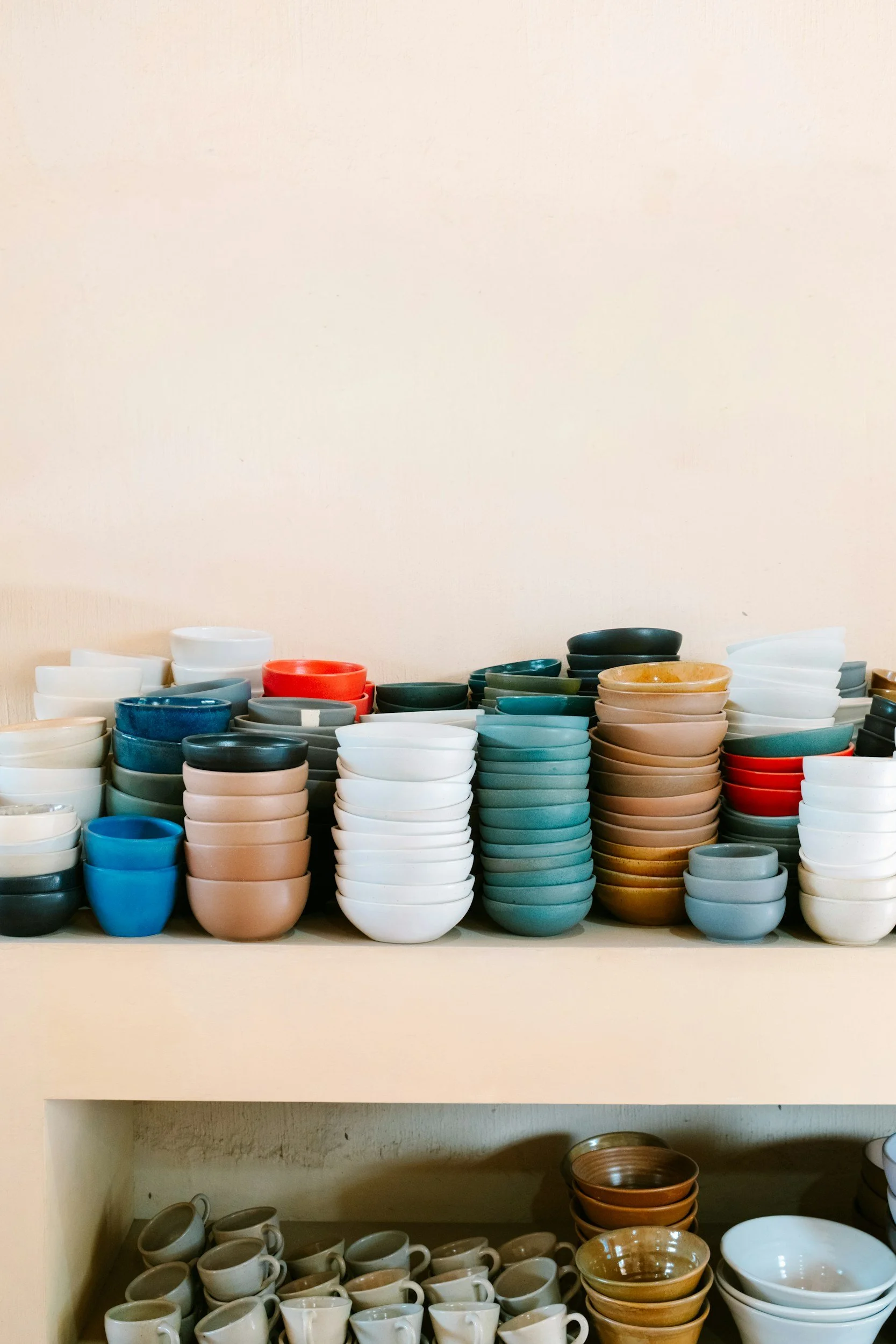 Shelf filled with stacked colorful bowls and cups in a display.