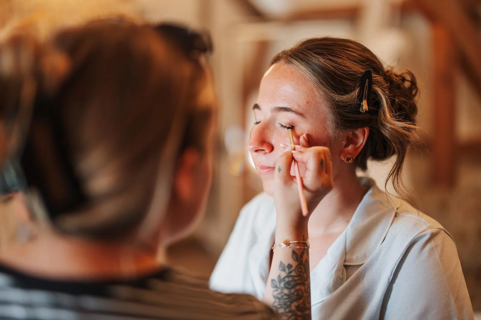 Beauty professional applying makeup to a woman's eyelid in a salon setting.