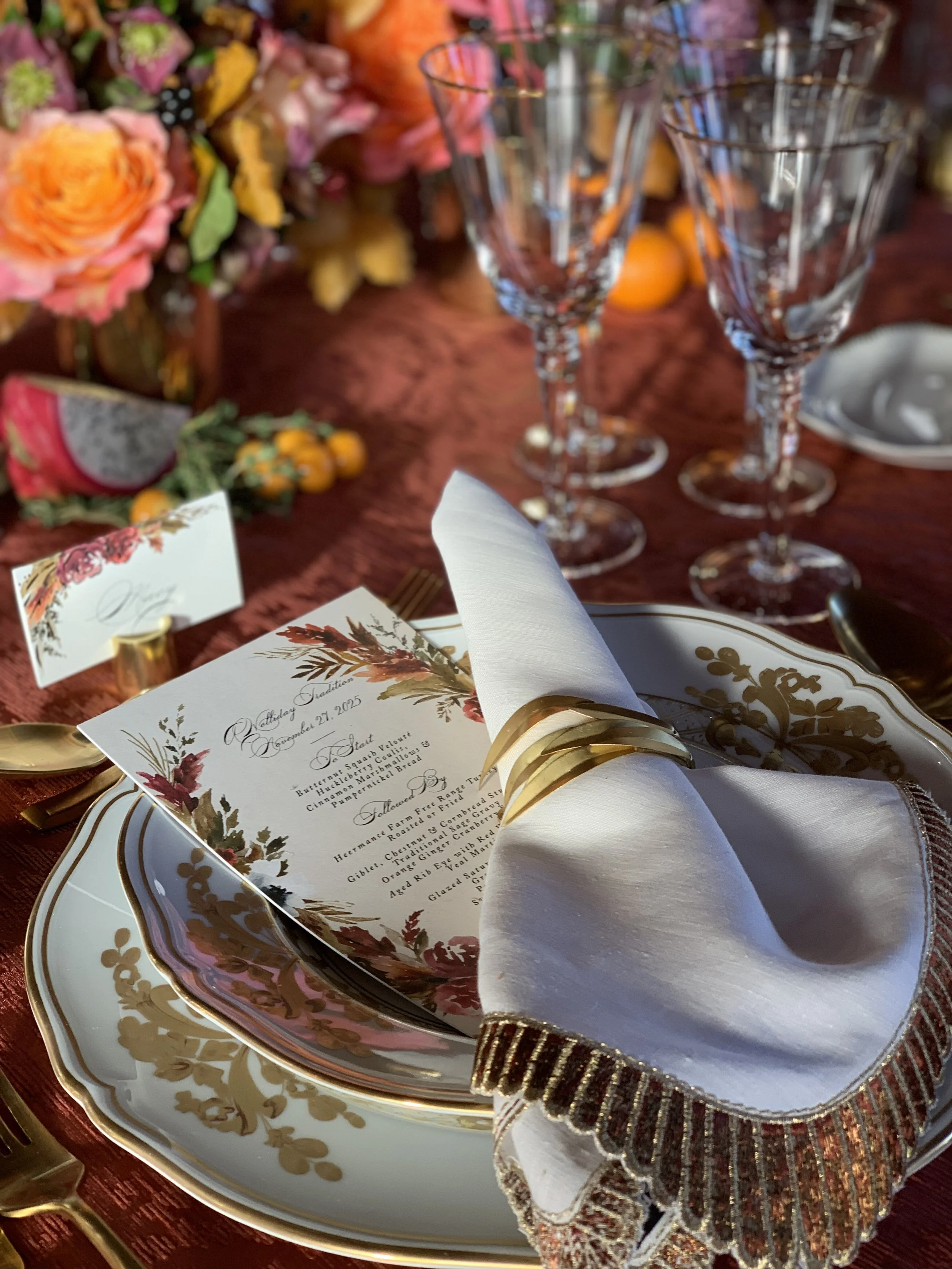 Elegant Thanksgiving dinner table setting with floral china, folded napkin, wine glasses, autumn flowers, and seasonal fruit