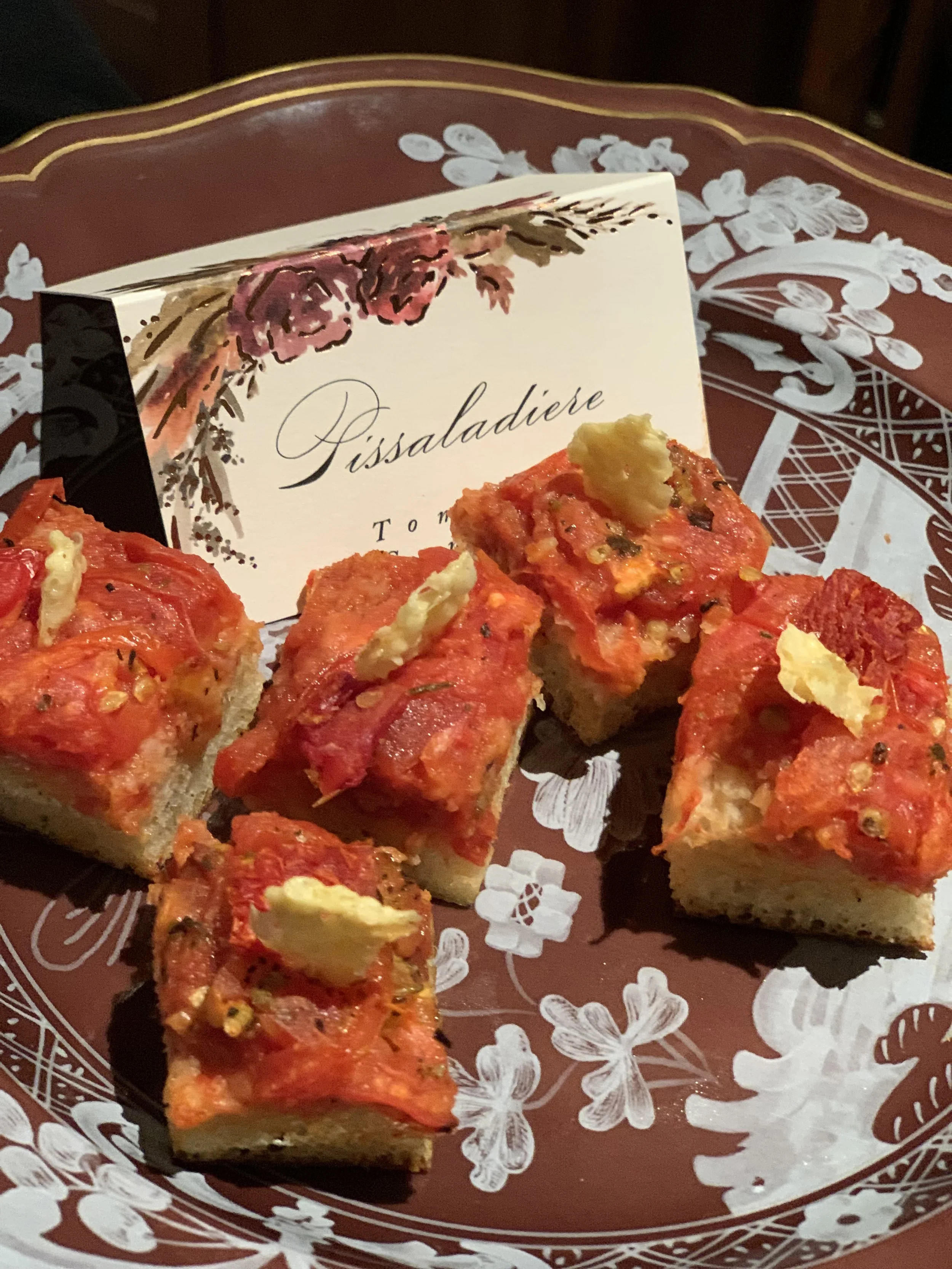 Sliced red pepper and cheese-topped pastry arranged on a floral plate beside a handwritten greeting card.