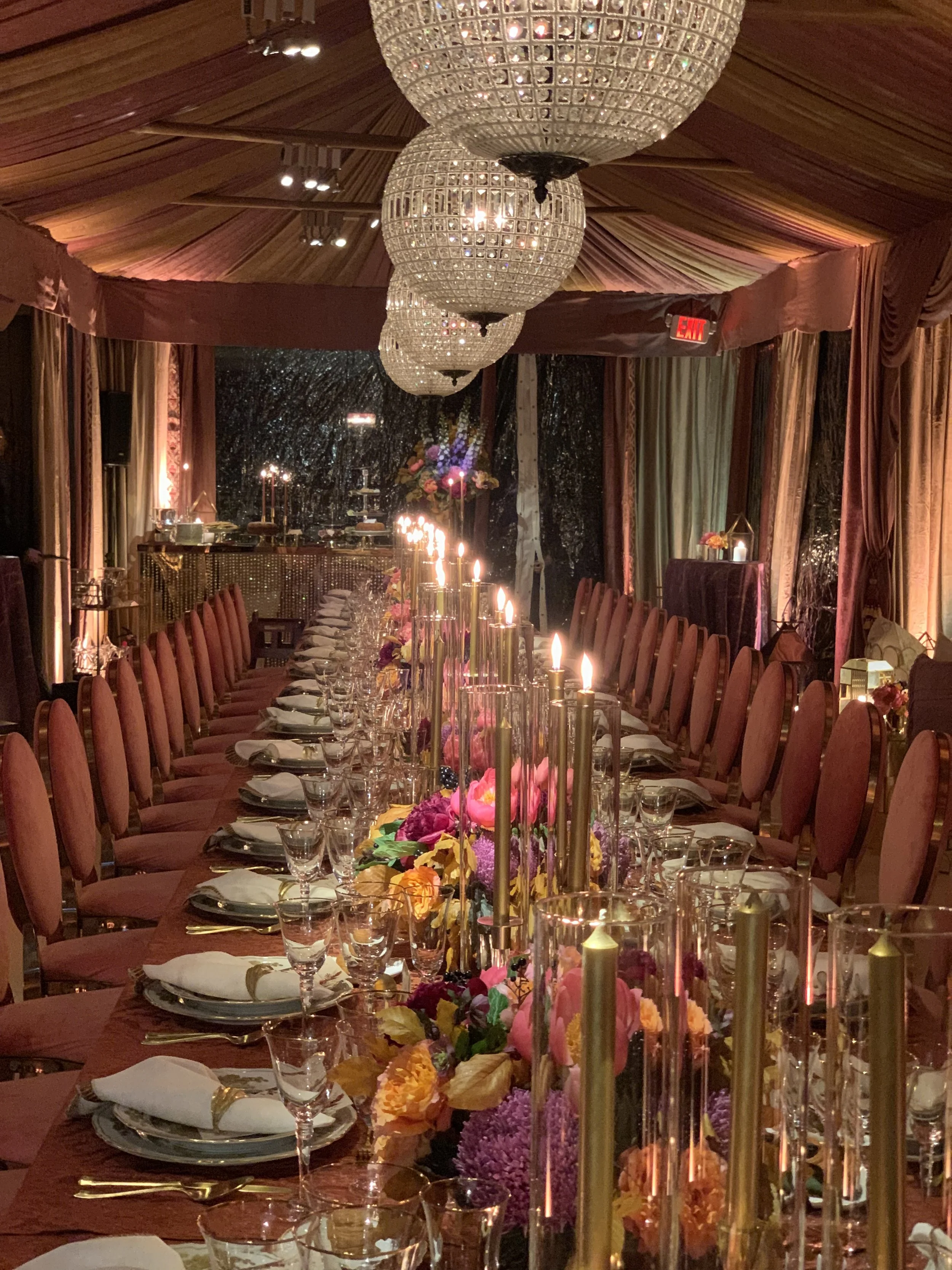 Elegant banquet hall with crystal chandeliers, candlelit floral centerpieces, and a long formal dining table.