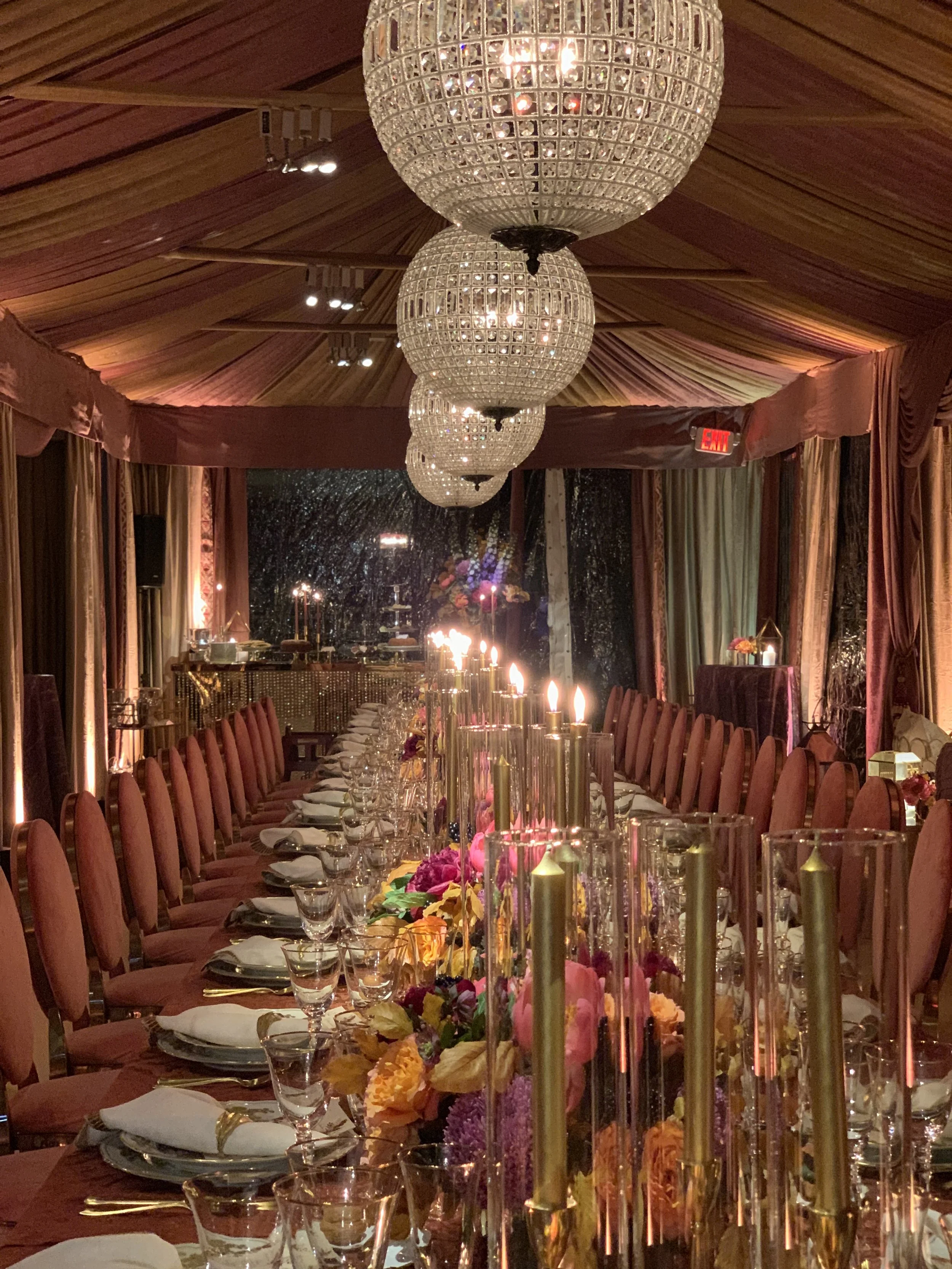 Elegant banquet hall with crystal chandeliers, candlelit floral centerpiece, and long formal dining table