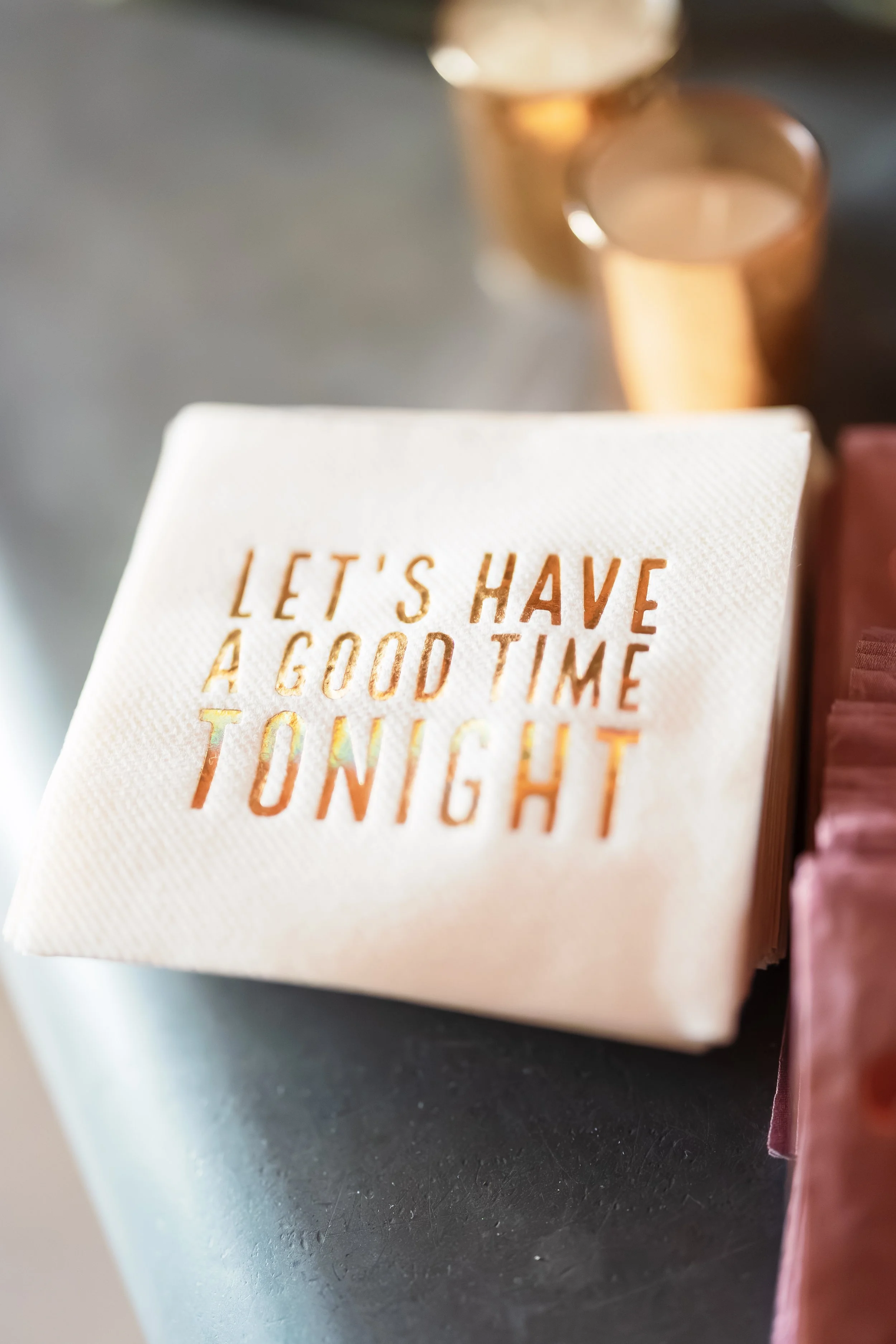 Close-up of a stemmed wine glass behind a book page reading “LET'S HAVE A GOOD TIME TOGETHER.”