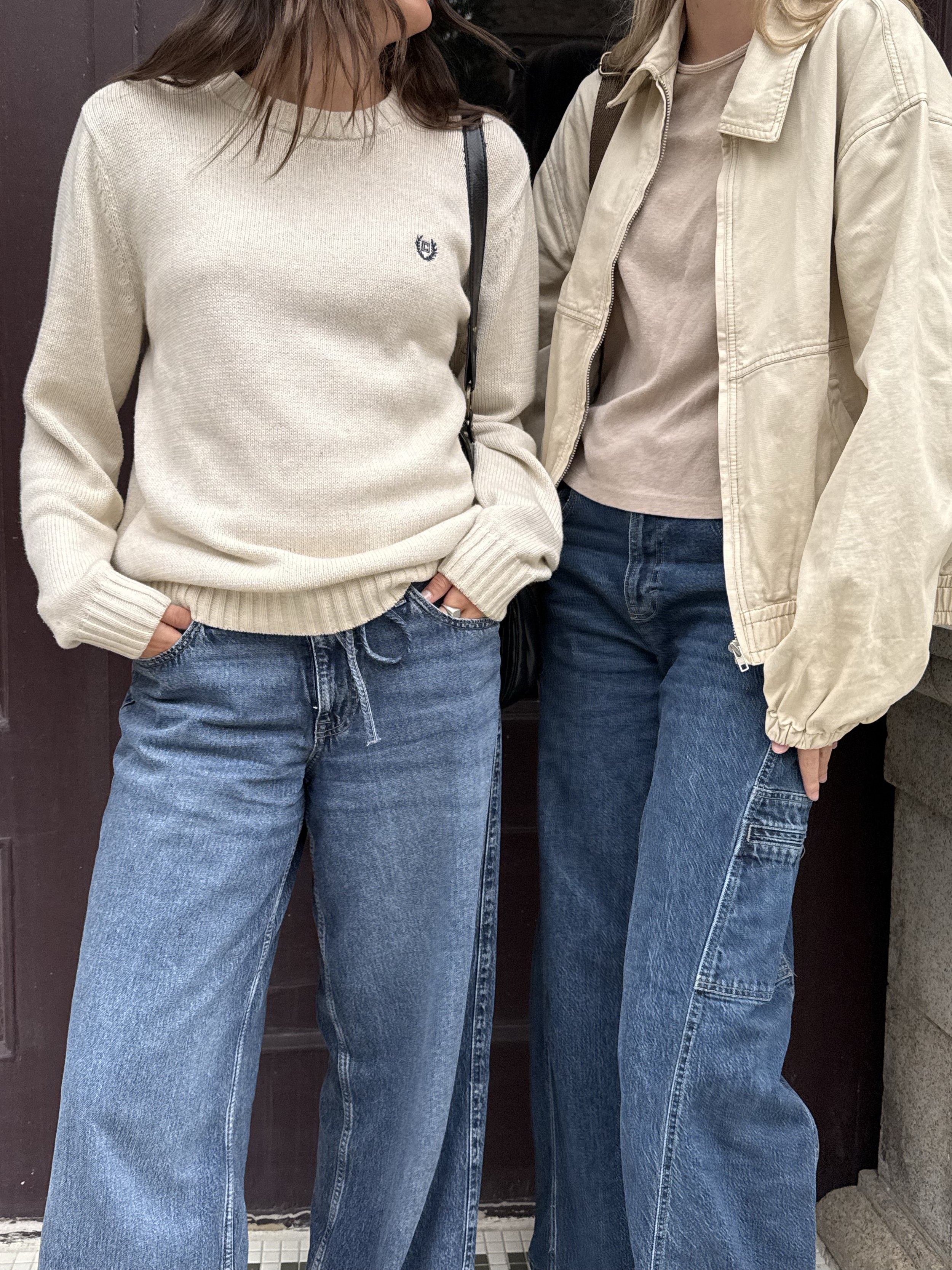 Two people modeling cream sweaters, beige jacket, and blue jeans