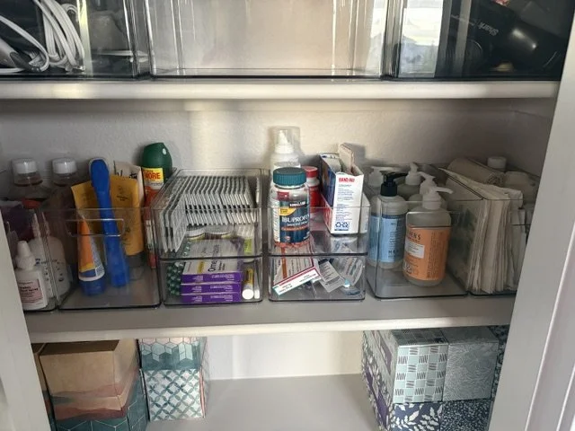 Organized bathroom medicine cabinet with medications, vitamins, toiletries, and storage baskets