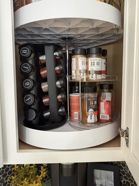 Rotating kitchen cabinet organizer filled with labeled spice jars and seasoning containers