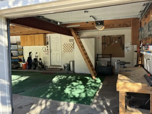 Organized residential garage with golf clubs, green floor mat, workbench, storage cabinets, and tools
