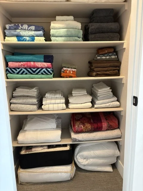 Organized linen closet with neatly folded towels, blankets, sheets, and bedding on shelves