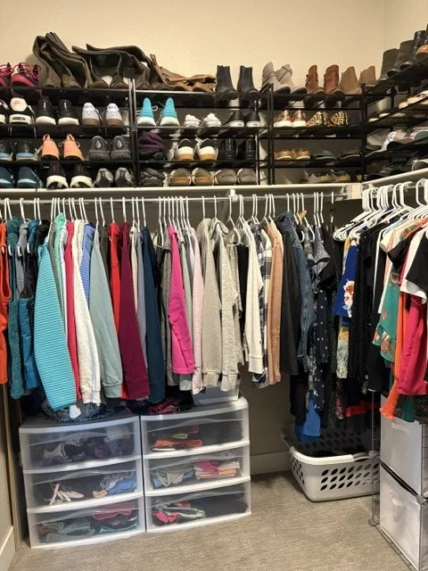Organized walk-in closet with shoe racks, hanging clothes, storage drawers, and laundry baskets